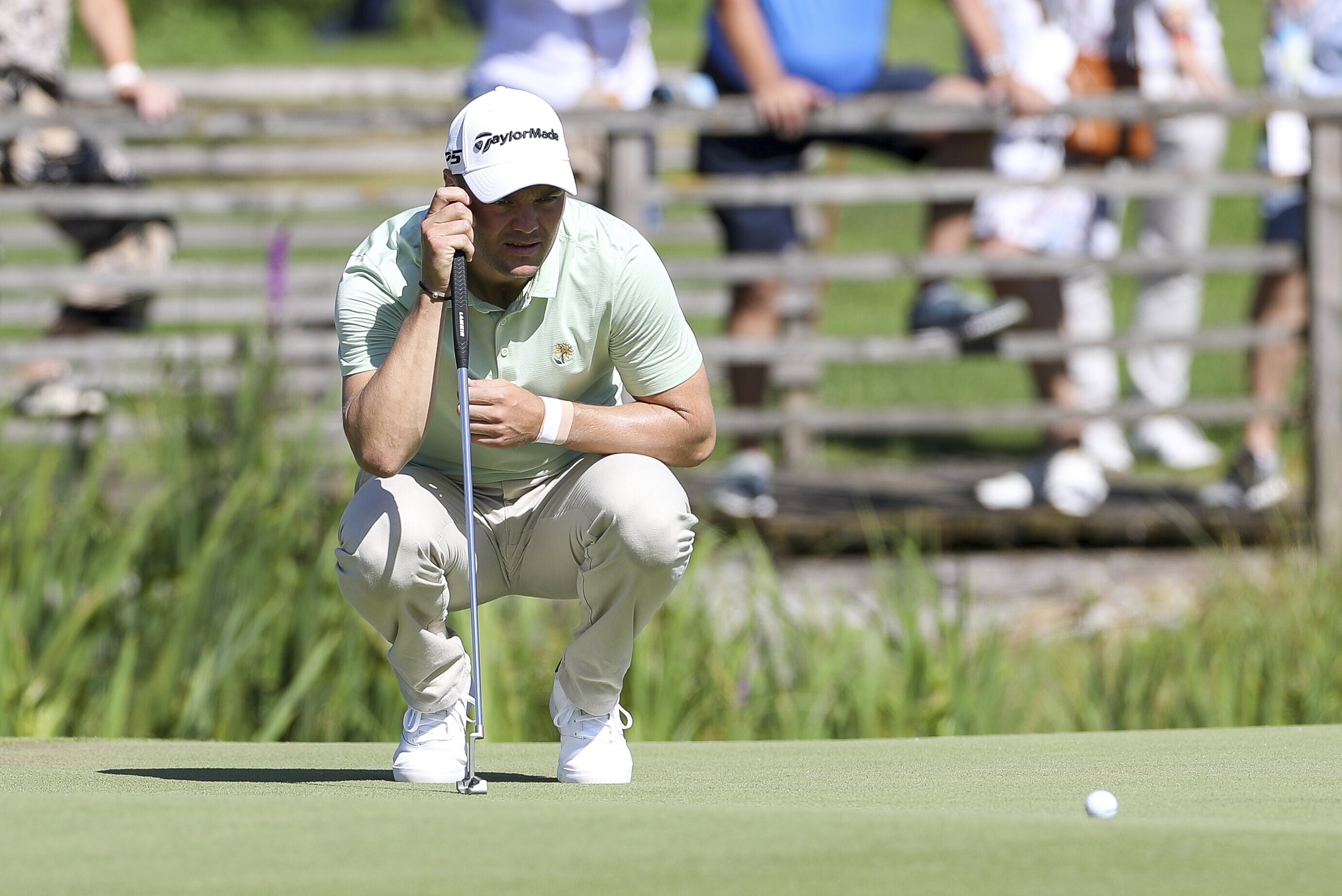 Germany's Martin Kaymer squats on the green during the German International Open golf tournament at Golfclub Muenchen Eichenried in Munich, Germany, Thursday, June 23, 2022. 