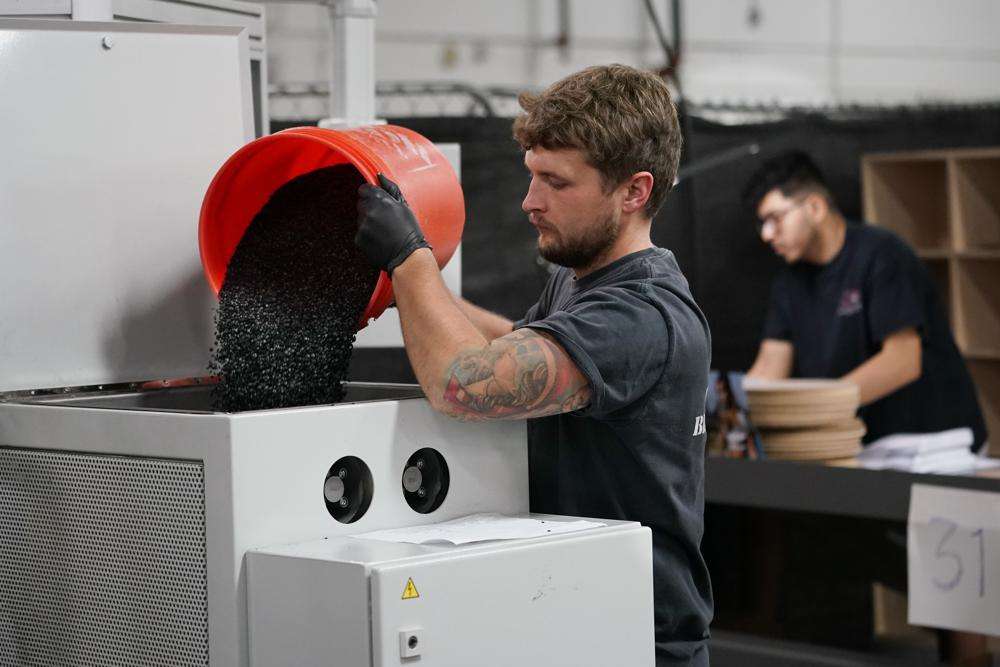 Thane Adolf dumps black vinyl pellets into a machine that will form the pellets into hockey puck-shaped "biscuits' to make vinyl record albums at the United Record Pressing facility Thursday, in Nashville, Tenn.