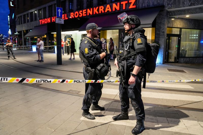 Security forces stand at the site where several people were injured during a shooting outside the London pub in central Oslo, Norway on Saturday.