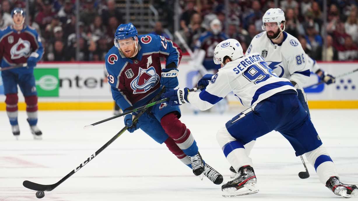 Colorado Avalanche center Nathan MacKinnon (29) moves the puck against Tampa Bay Lightning defenseman Mikhail Sergachev (98) during the second period in Game 5 of the NHL hockey Stanley Cup Final, Friday, June 24, 2022, in Denver.