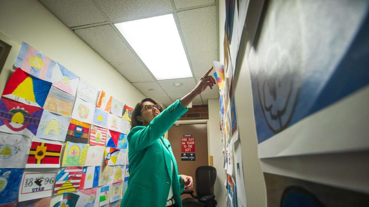Lt. Gov. Deidre Henderson points to one of the 5,703 Utah state flag designs posted to the walls of the Utah office building in Millcreek on June 23. The Utah Legislature could meet for a special session next month to approve a new state flag recommended by the Utah State Flag Task Force.