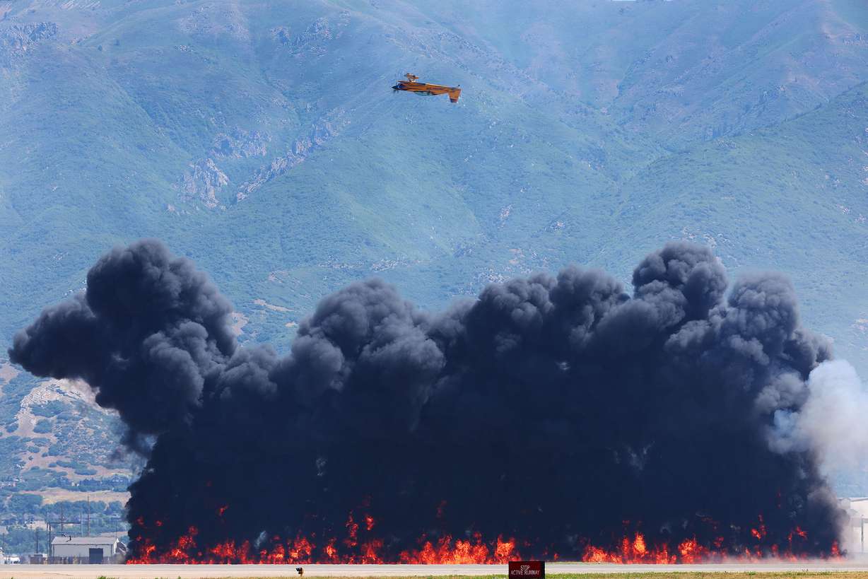 Bob Freeman flies upside down in his 330XL stunt plane over pyrotechnics during Warriors Over the Wasatch Air and Space Show at Hill Air Fore Base in Layton on Saturday.