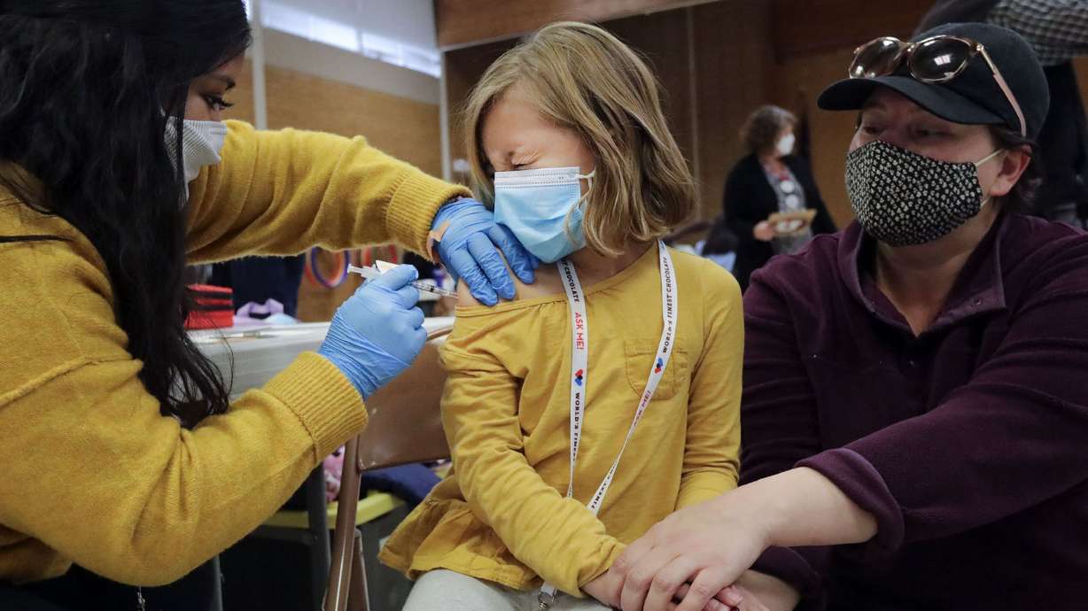 Claudia Ceron, a Salt Lake County Health Department community health worker and vaccinator, gives Etta Bastian, 7, a COVID-19 vaccination as Etta’s mother, Courtney Bastian, holds her hand at Hillsdale Elementary School in West Valley City on Nov. 8, 2021.