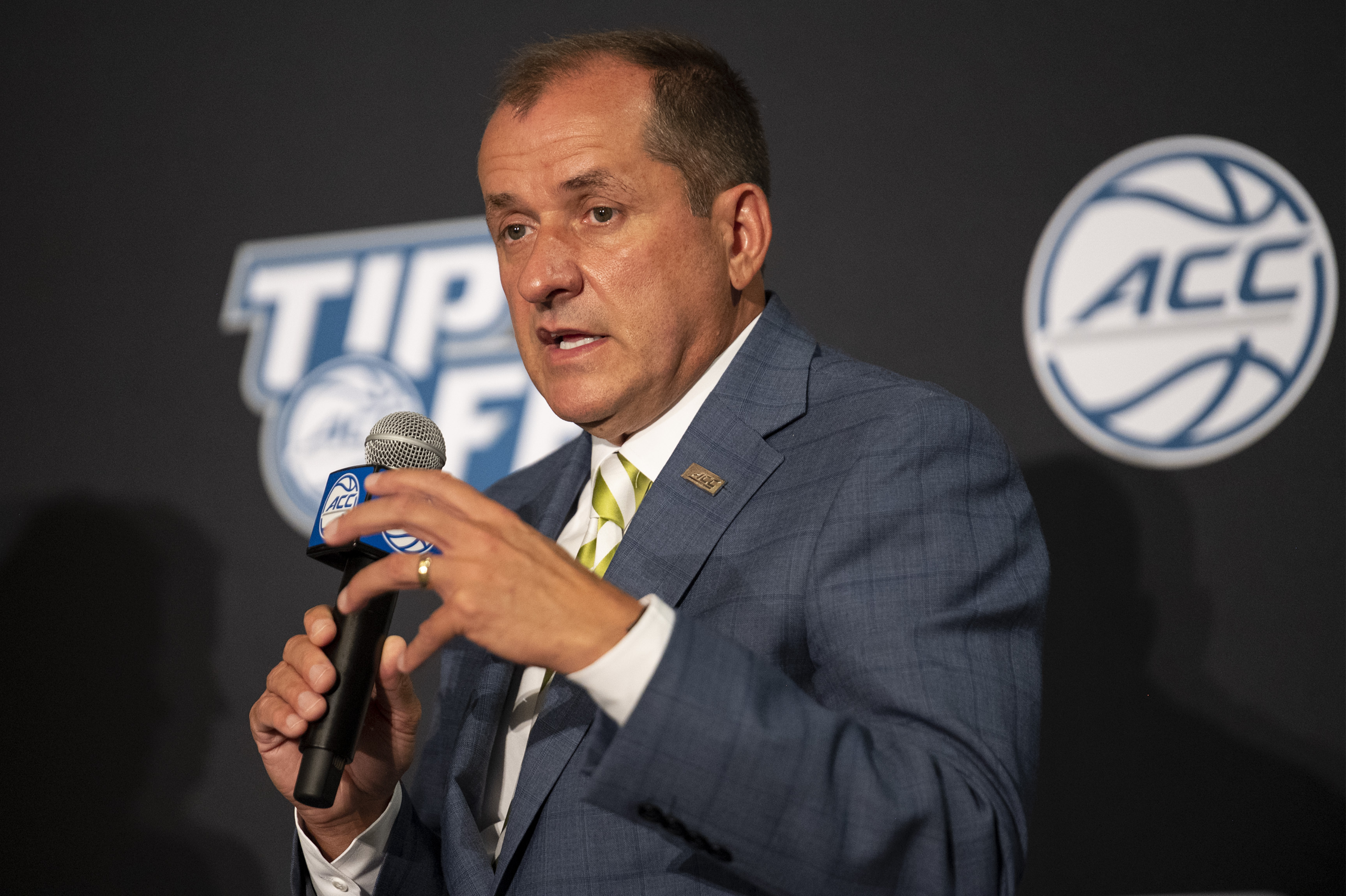 FILE - Atlantic Coast Conference Commissioner Jim Phillips speaks during NCAA college basketball ACC media day, Tuesday, Oct. 12, 2021, in Charlotte, N.C. The ACC is going forward with a plan to change its football scheduling model, with the biggest change being the elimination of divisions. “The future ACC football scheduling model provides significant enhancements for our schools and conference, with the most important being our student-athletes having the opportunity to play every school both home and away over a four-year period,” ACC Commissioner Jim Phillips said. 