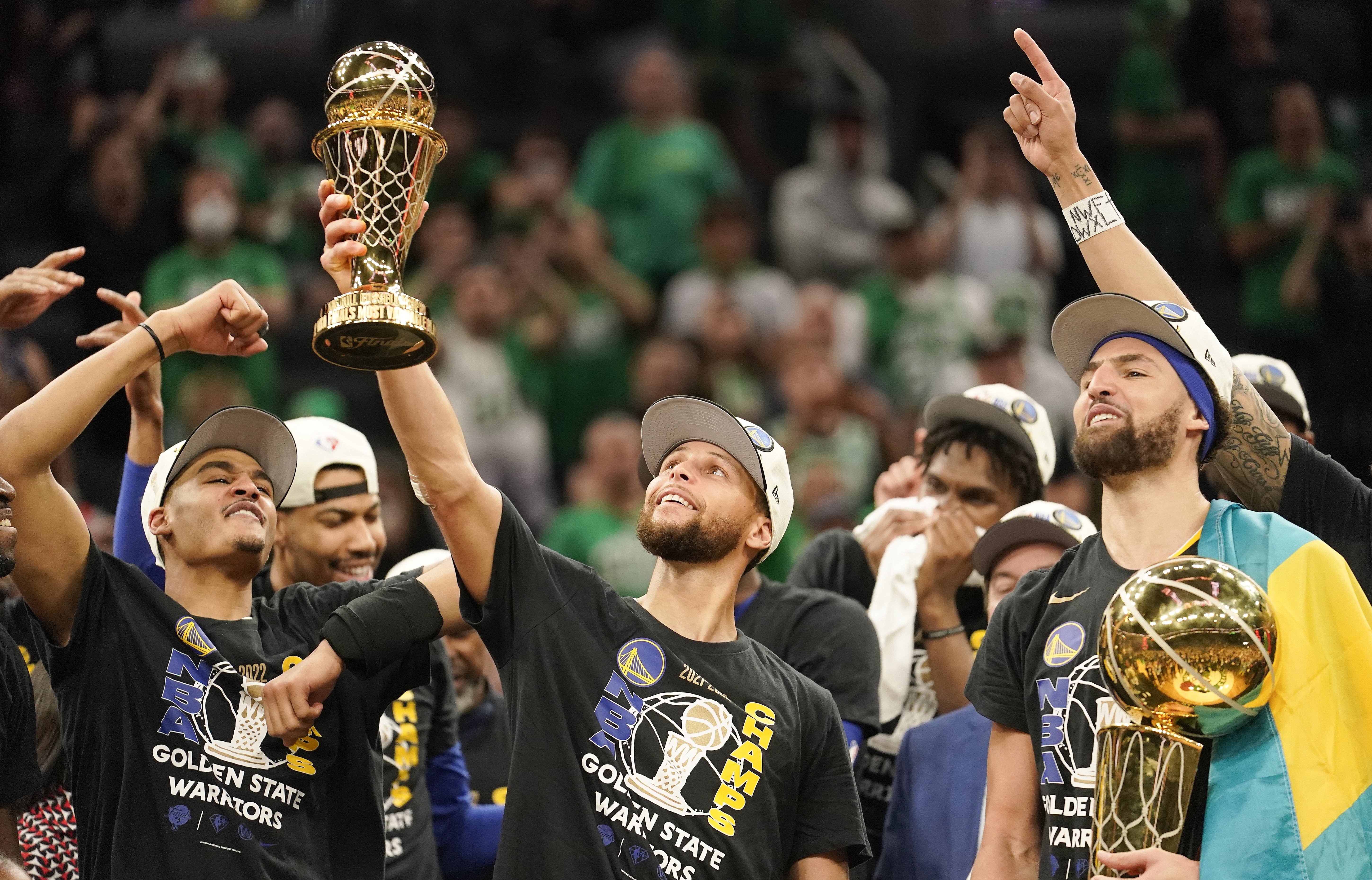 Golden State Warriors guard Stephen Curry, center, holds up the Bill Russell Trophy for most valuable player after the Warriors defeated the Boston Celtics in Game 6 to win basketball's NBA Finals championship, Thursday, June 16, 2022, in Boston. 