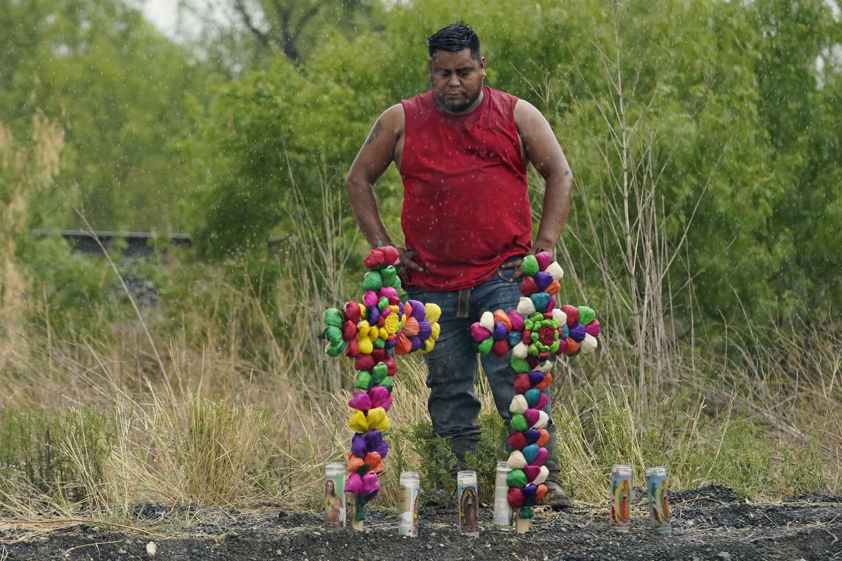 Rain falls as a man pays his respects at the site where officials found dozens of people dead in a semitrailer containing suspected migrants, Tuesday, in San Antonio.