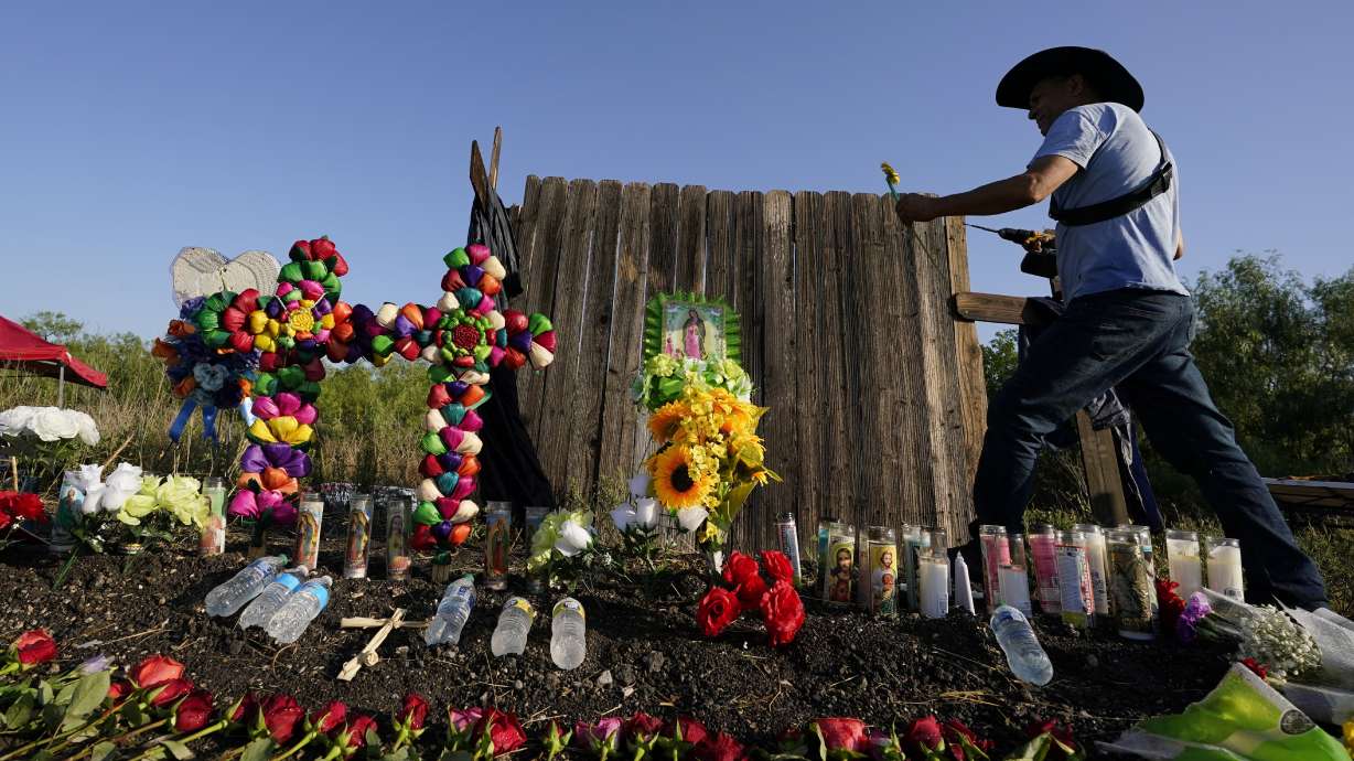 Roberto Marquez of Dallas adds a flower a makeshift memorial at the site where officials found dozens of people dead in an abandoned semitrailer containing suspected migrants, Wednesday, in San Antonio.