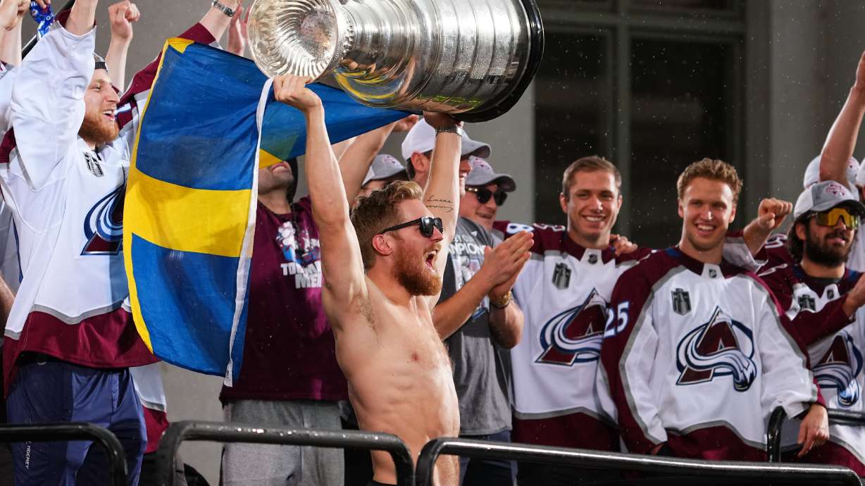 Colorado Avalanche left wing Gabriel Landeskog hoists the Stanley Cup and a flag of Sweden at a rally for the NHL hockey champions Thursday, June 30, 2022, in Denver.