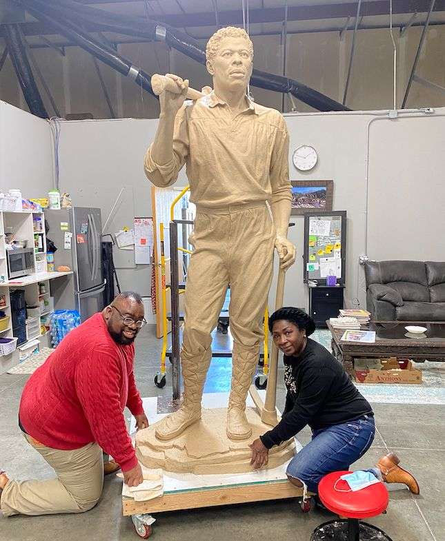 Left, Kellen Perkins, a descendant of Green Flake and Jane Manning James, and Tamu Smith, a producer of the film, “His Name is Green Flake,” kneel next to a new statue of Green Flake by Stephanie and Roger Hunt.