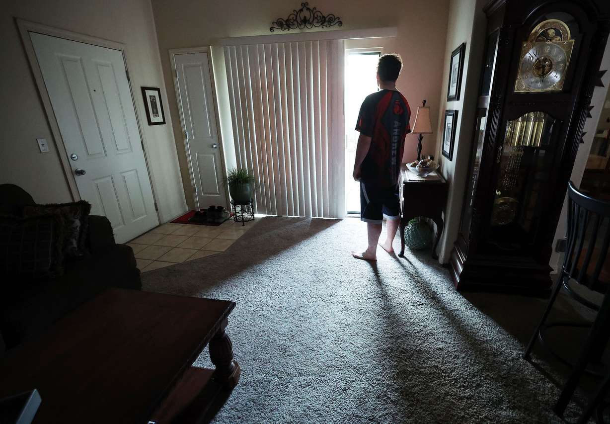 Andrew Asay looks out of the door at his apartment in Pleasant Grove on June 21. Asay shares the apartment with his mother and sister, and they are buying a house together.