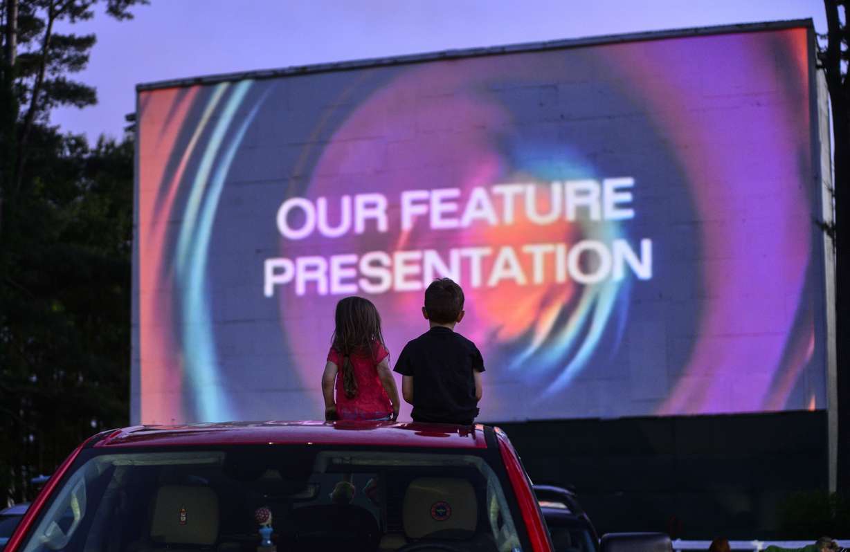Arya Mohan, 3, and her brother, Frankie, 5, from Athol, Mass., sit on the roof of their grandparent's truck during the start of a movie at the Northfield Drive-In, in Hinsdale, N.H., on June 10. The fast-changing coronavirus has kicked off summer in the U.S. with lots of infections but relatively few deaths compared to its prior incarnations.