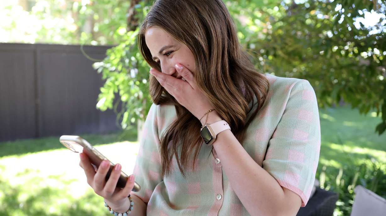 Megan Grass laughs while looking through her photos and videos of her at the Australia Zoo at home in Cottonwood Heights on June 21. Grass posted a TikTok video, that has gone viral, of her asking Robert Irwin, son of “The Crocodile Hunter” Steve Irwin, for his number.