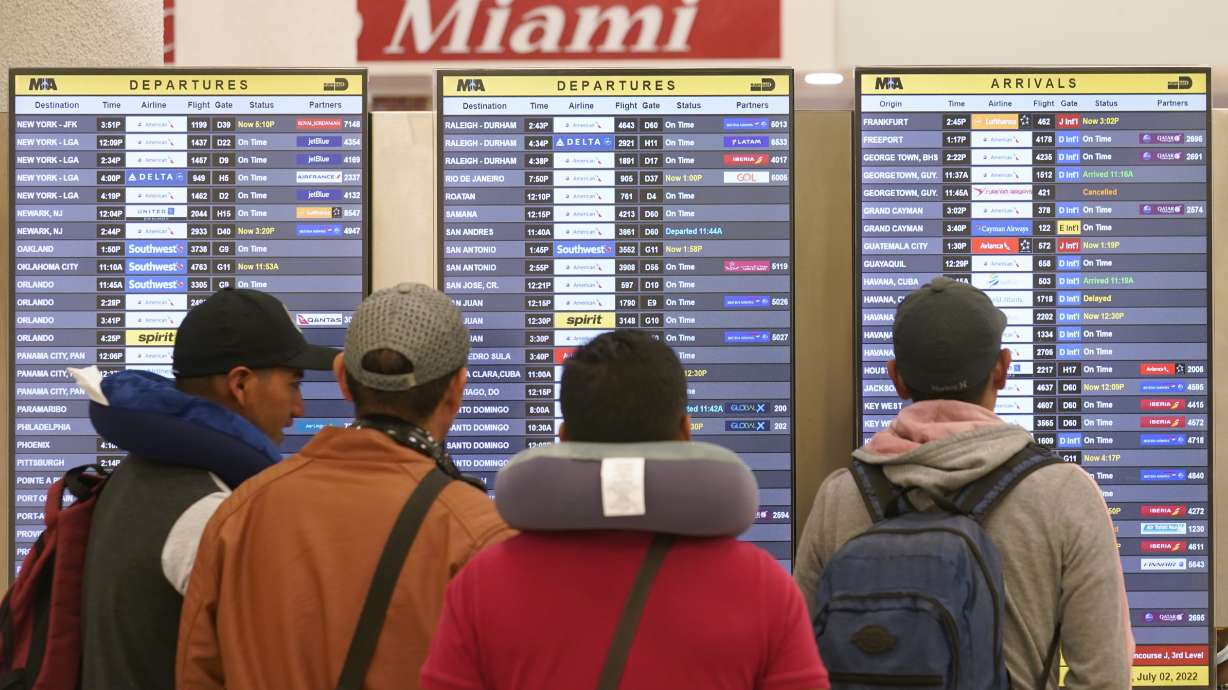 Travelers check their flights at Miami International Airport, Saturday, in Miami. The Fourth of July holiday weekend is jamming U.S. airports with the biggest crowds since the pandemic began in 2020.