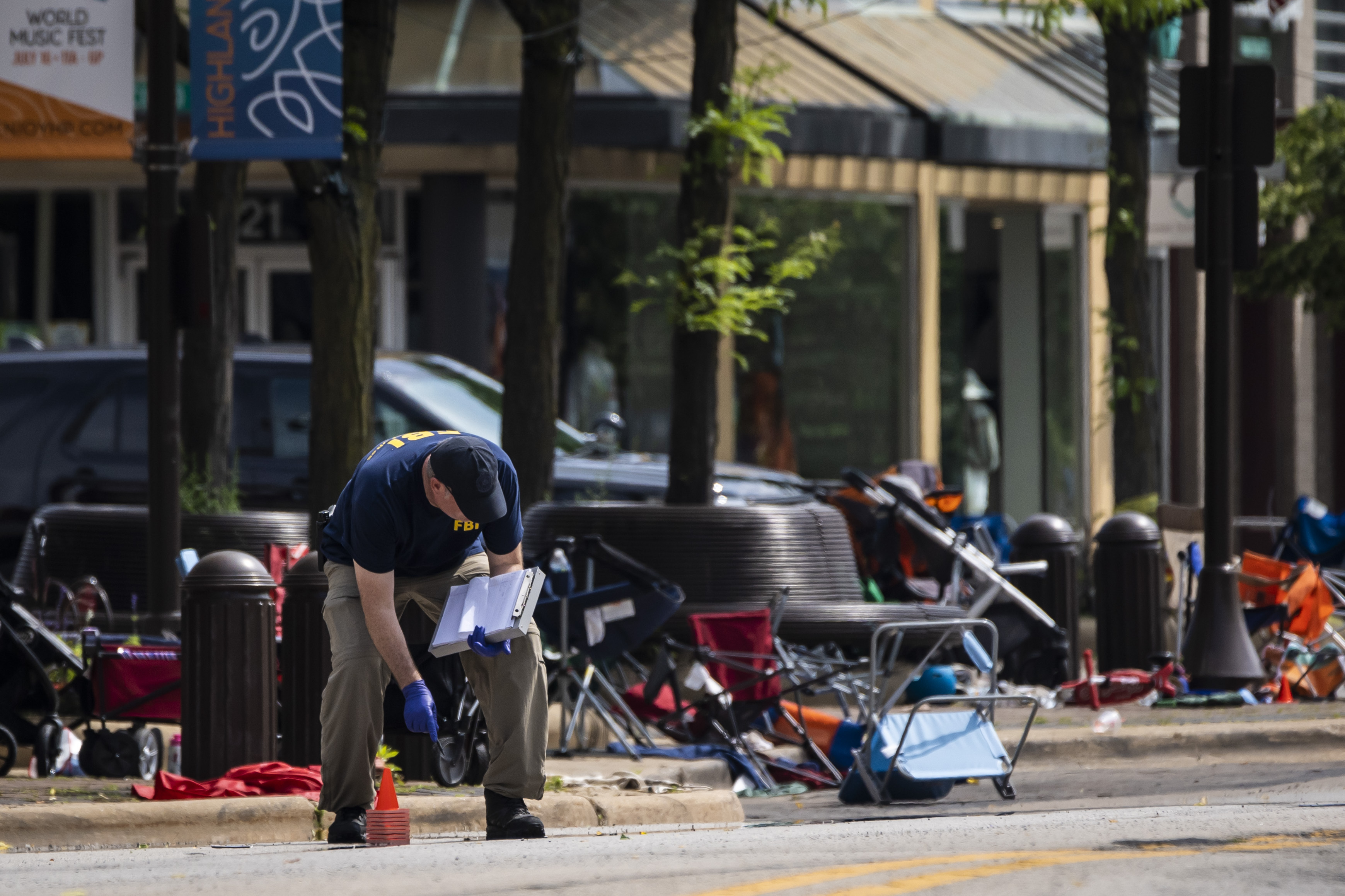 Members of the FBI's Evidence Response Team Unit investigate in downtown Highland Park, Ill., the day after a deadly mass shooting on Tuesday. Police say the gunman who attacked an Independence Day parade in suburban Chicago fired more than 70 rounds with an AR-15-style gun.   