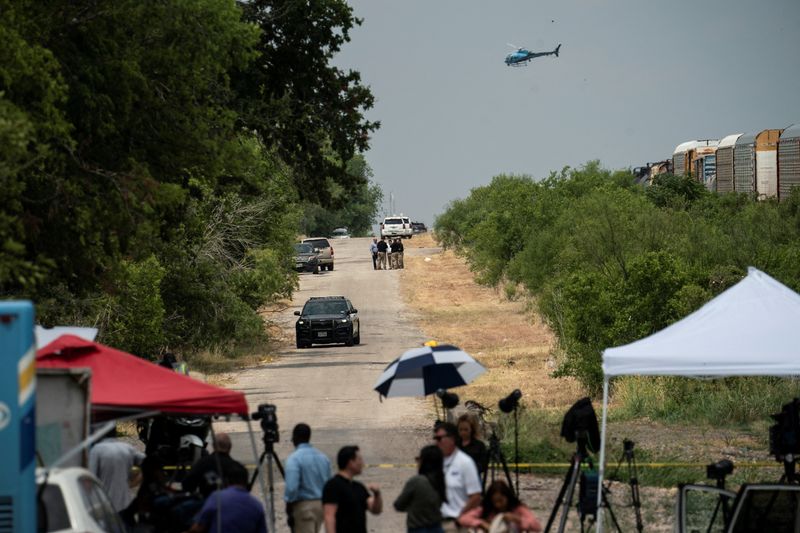 Law enforcement officers work at the scene as a helicopter flies over where dozens of people were found dead inside a trailer truck in San Antonio, Texas, June 28. A week after 53 migrants died in a sweltering trailer in San Antonio, Texas, officials from at least four different countries face challenges in identifying the victims of the deadliest U.S. human smuggling tragedy on record.
