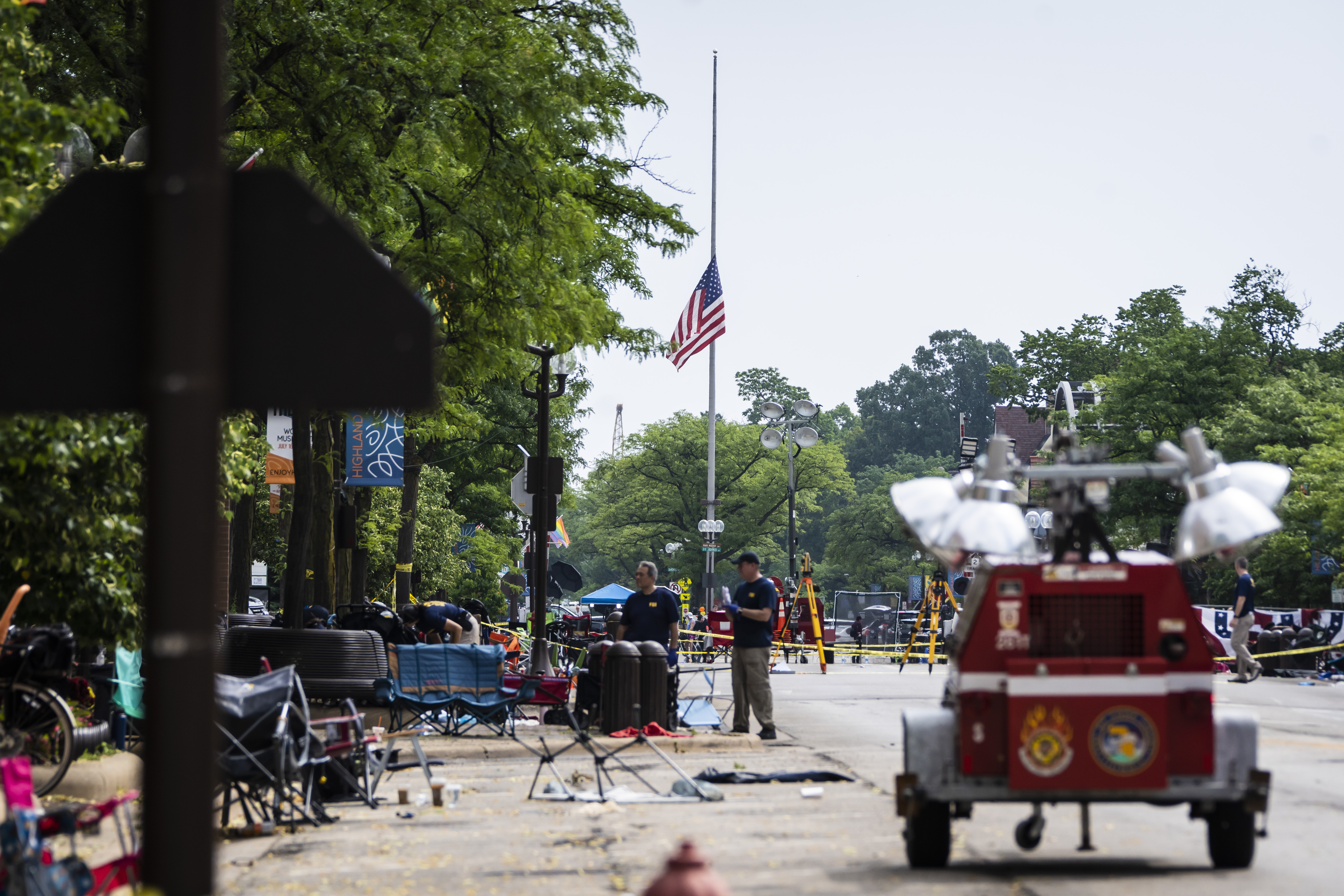 A flag hangs at half staff as members of the FBI's Evidence Response Team Unit investigate in downtown Highland Park, Ill., the day after a deadly mass shooting on Tuesday. Police say the gunman who attacked an Independence Day parade in suburban Chicago fired more than 70 rounds with an AR-15-style gun.