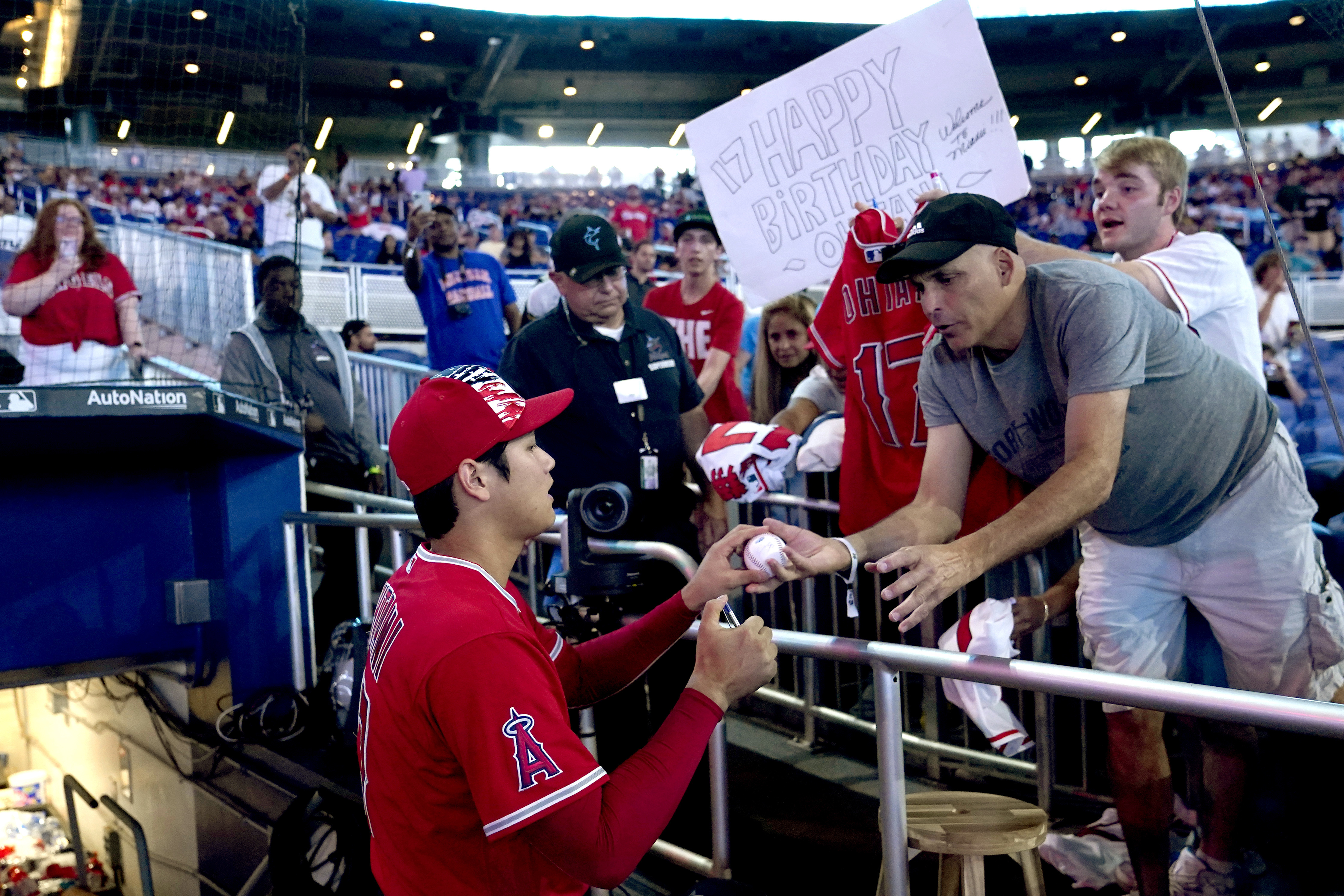 A fan holds a happy birthday sign as Los Angeles Angels' Shohei Ohtani signs autographs before the team's baseball game against the Miami Marlins, Tuesday, July 5, 2022, in Miami. Ohtani turned 28 on Tuesday. 