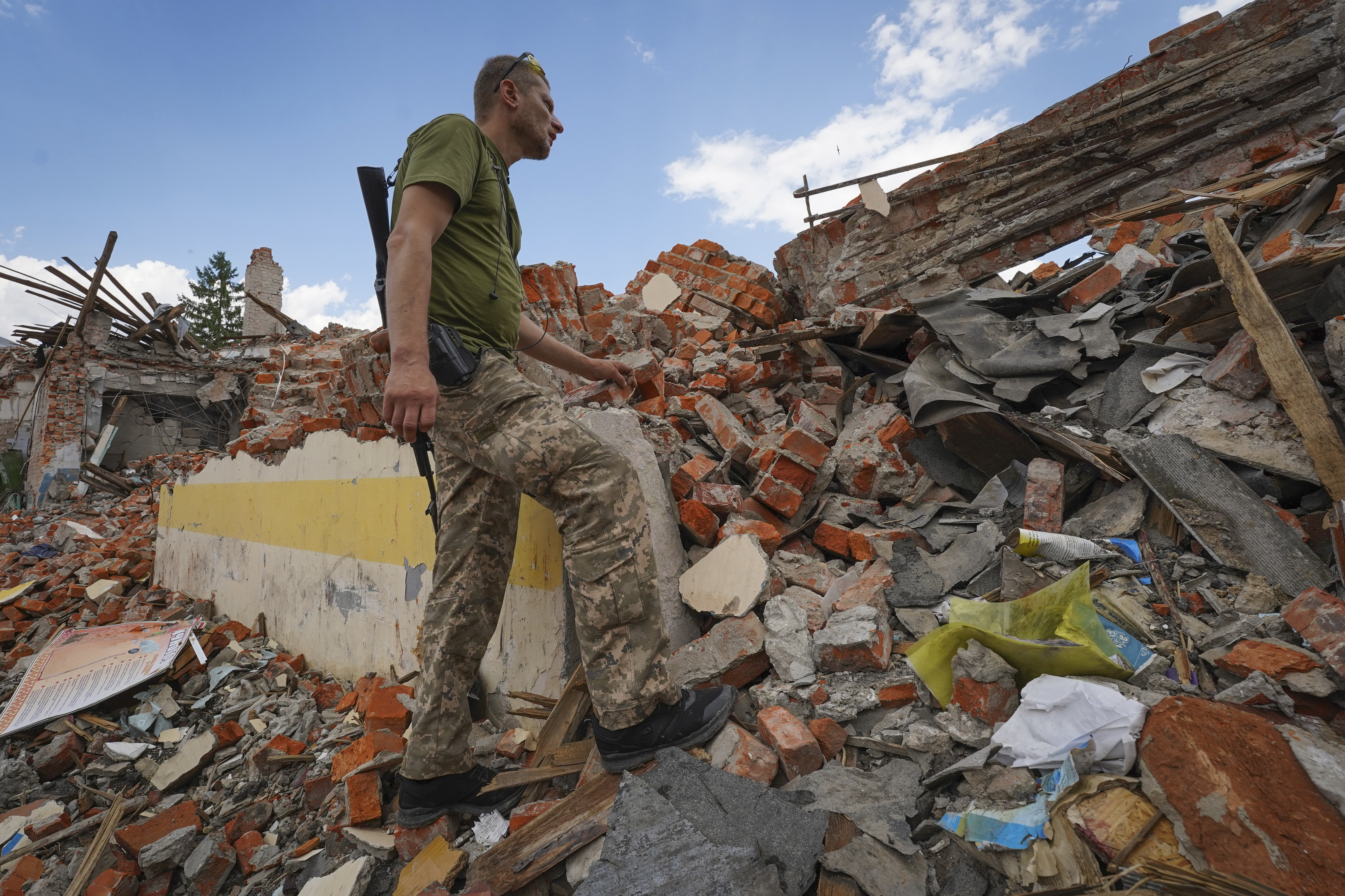 A Ukrainian serviceman looks at the rubble of a school that was destroyed some days ago during a missile strike in outskirts of Kharkiv, Ukraine, Tuesday. 