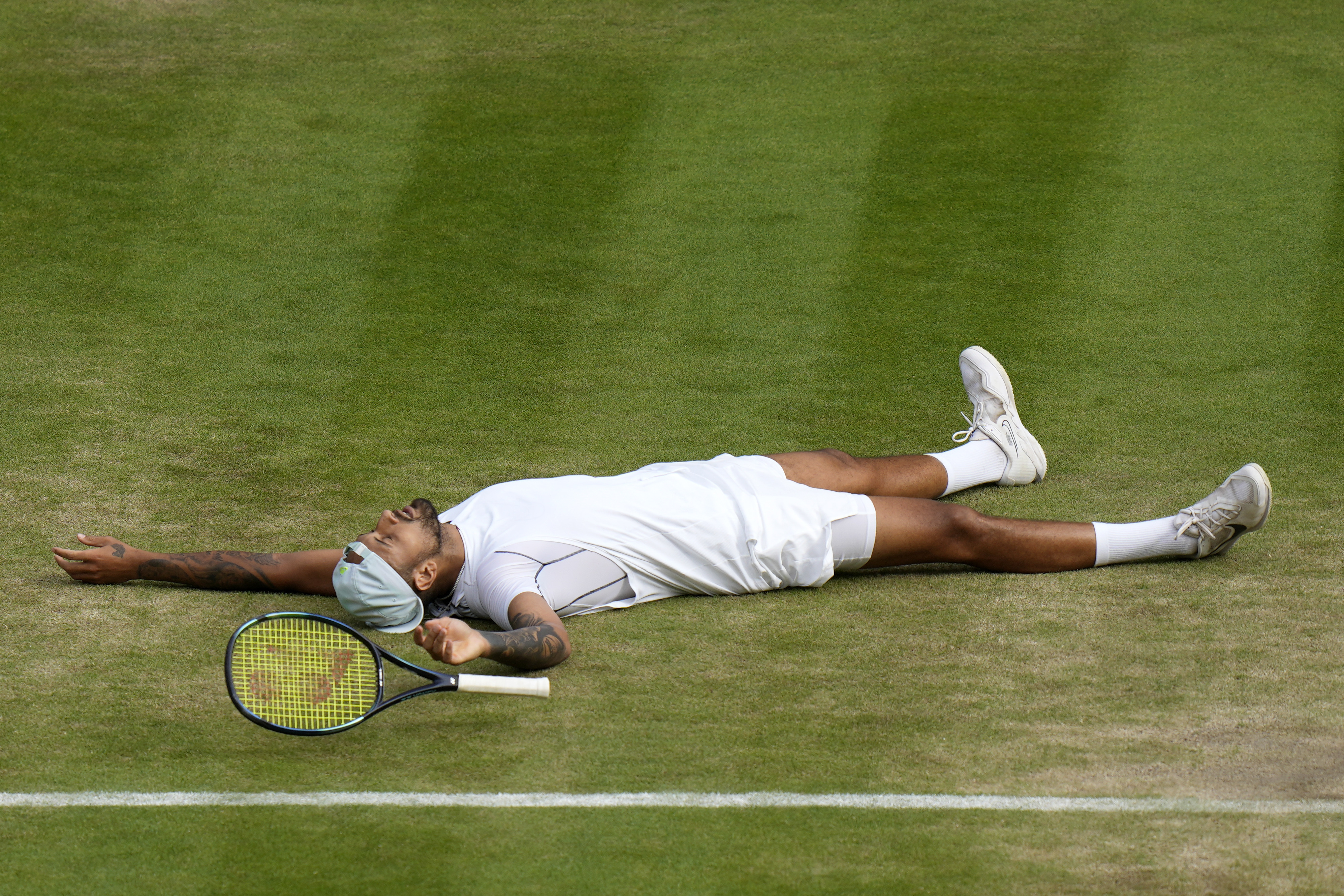 Australia's Nick Kyrgios lies on the ground after defeating Chile's Cristian Garin during a men's singles quarterfinal match on day ten of the Wimbledon tennis championships in London, Wednesday, July 6, 2022.