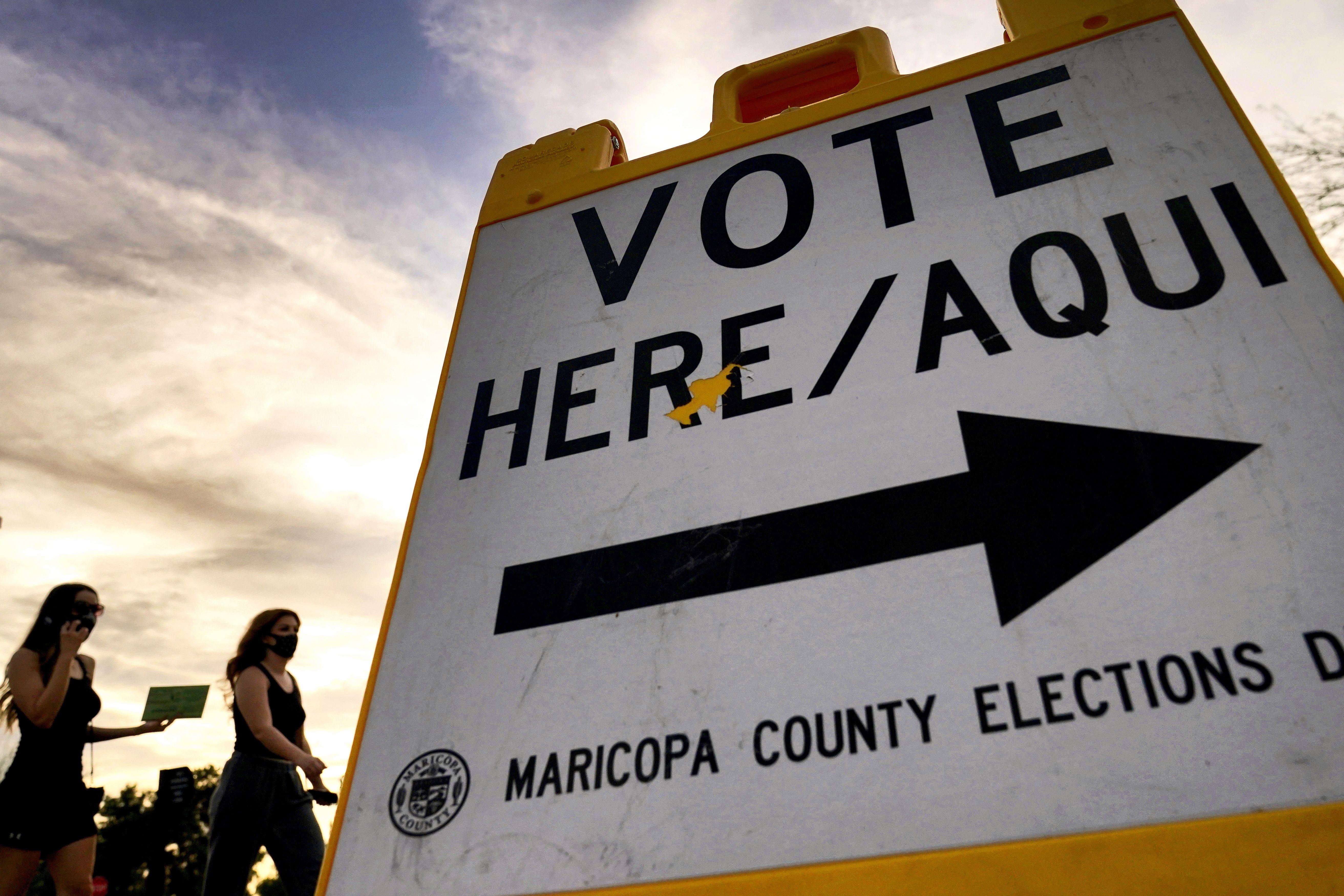 Voters deliver their ballot to a polling station in Tempe, Arizona, on Nov. 3, 2020. The U.S. Department of Justice on Tuesday sued Arizona over a new law requiring people who use a federal form to register to vote to provide additional proof of citizenship if they want to vote for president or using the state’s popular vote-by-mail system.