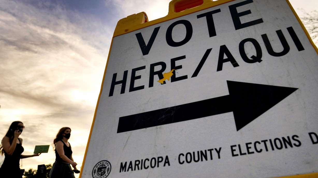Voters deliver their ballot to a polling station in Tempe, Arizona, on Nov. 3, 2020. The U.S. Department of Justice on Tuesday sued Arizona over a new law requiring people who use a federal form to register to vote to provide additional proof of citizenship if they want to vote for president or using the state’s popular vote-by-mail system.
