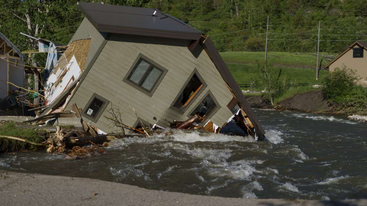 A house sits in Rock Creek after floodwaters washed away a road and a bridge in Red Lodge, Mont., on June 15. As cleanup from historic floods at Yellowstone National Park grinds on, climate experts and meteorologists say the gap between the destruction in the area and what was forecast underscores a troublesome trend tied to climate change.