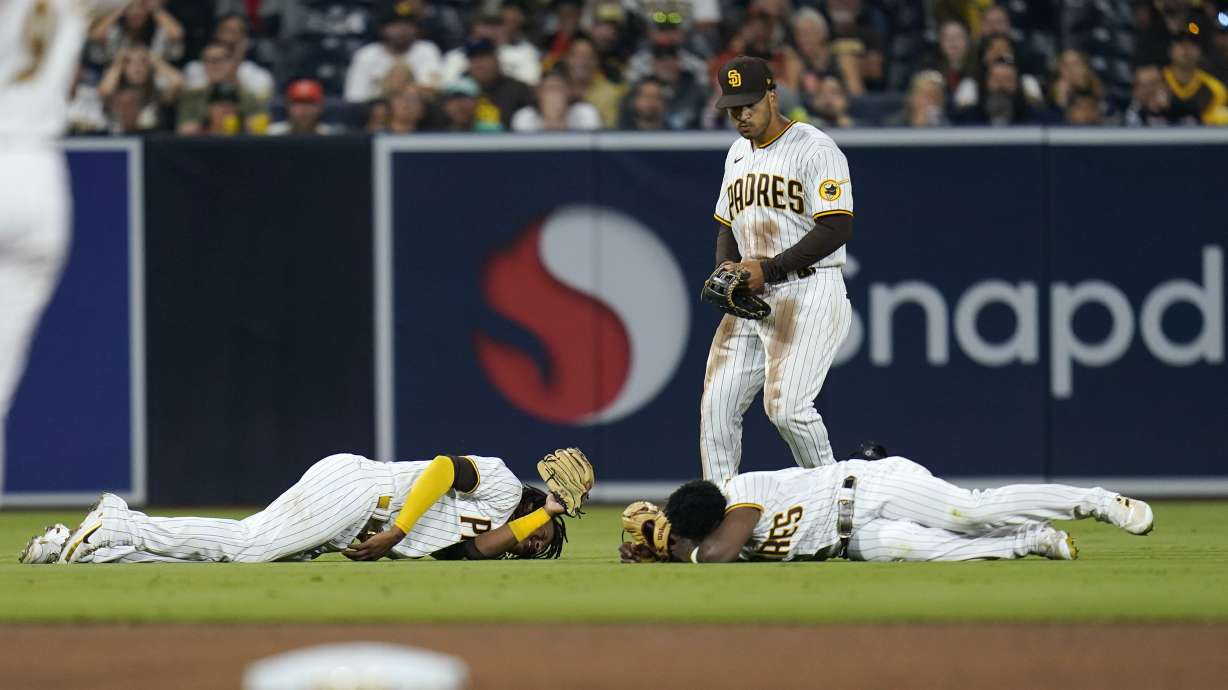 San Diego Padres shortstop C.J. Abrams, left, and left fielder Jurickson Profar, bottom right, react after colliding as center fielder Trent Grisham, center, looks on during the fifth inning of a baseball game against the San Francisco Giants, Thursday, July 7, 2022, in San Diego. Profar and Abrams collided as Abrams made a catch for an out against Giants' Tommy La Stella.