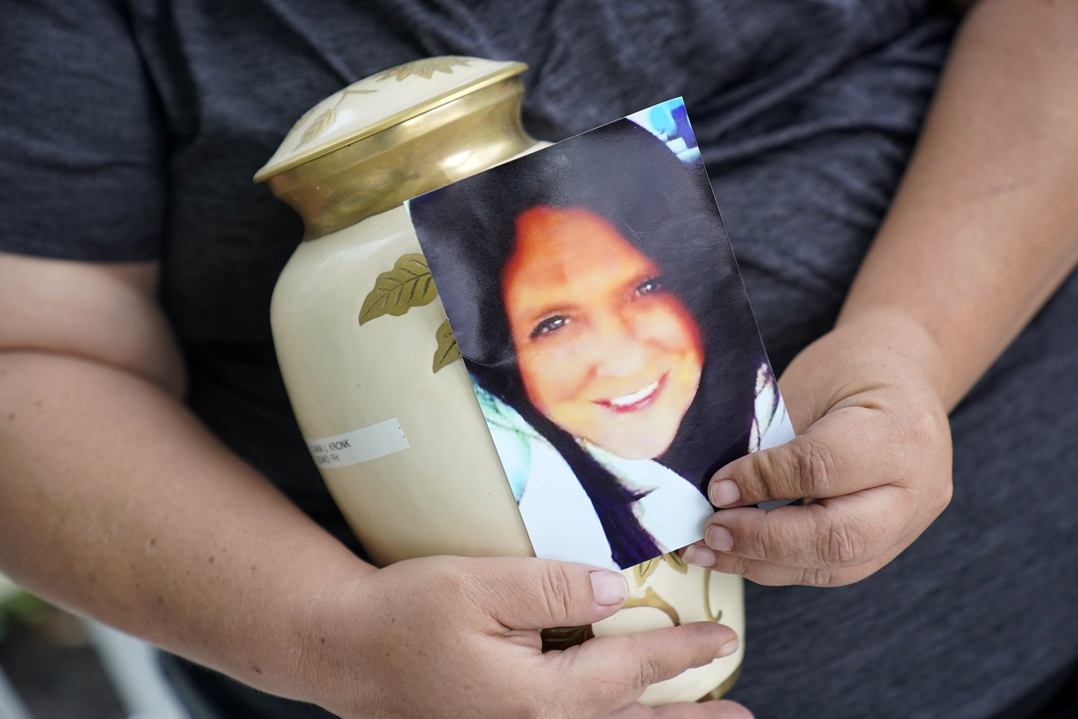 Kelly Titchenell sits on her porch in Mather, Pa., holding a photo of her mother Diania Kronk, and an urn containing her mother's ashes, Thursday. A Greene County, Pa., detective last week filed charges against 911 operator Leon “Lee” Price, 50, of Waynesburg, in the July 2020 death of Diania Kronk, 54, based on Price's reluctance to dispatch help without getting more assurance that Kronk would actually go to the hospital. 