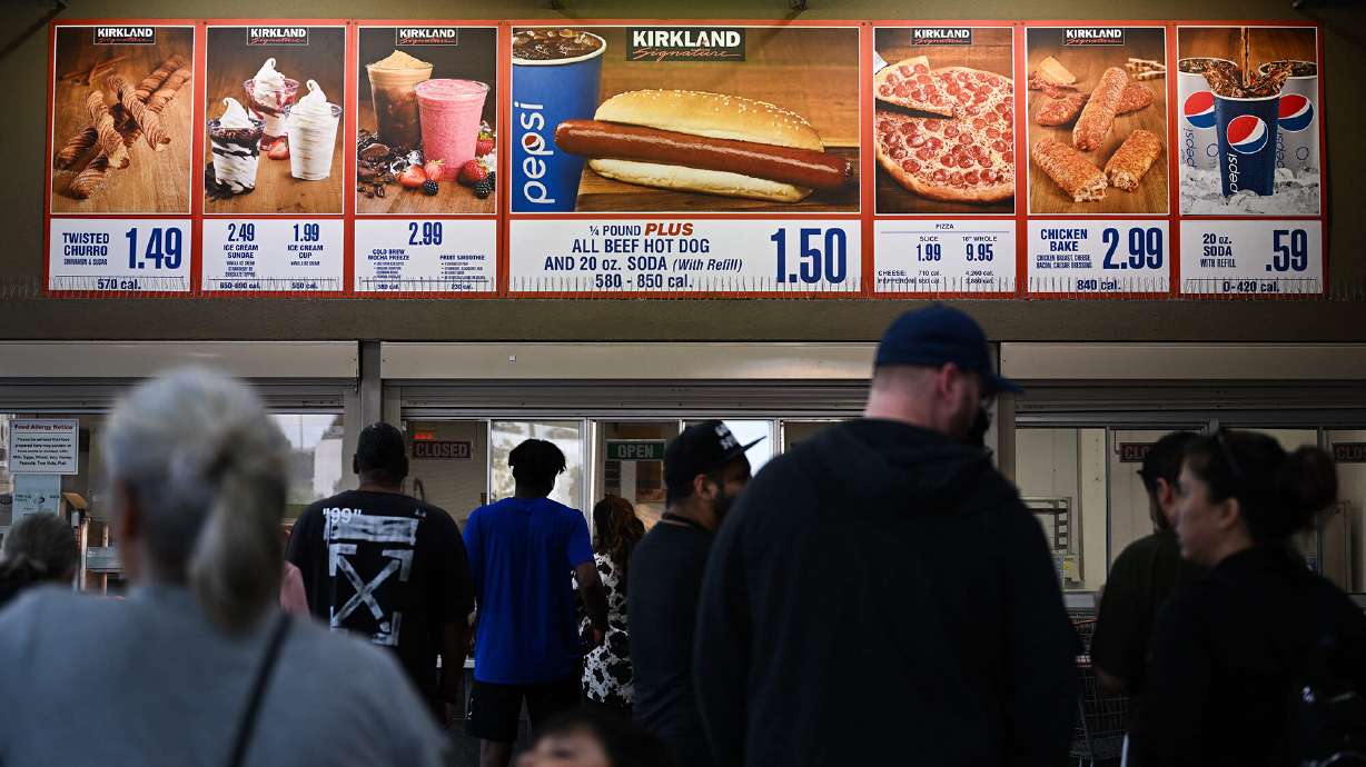 Customers wait in line to order below signage for the Costco Kirkland Signature $1.50 hot dog and soda combo.