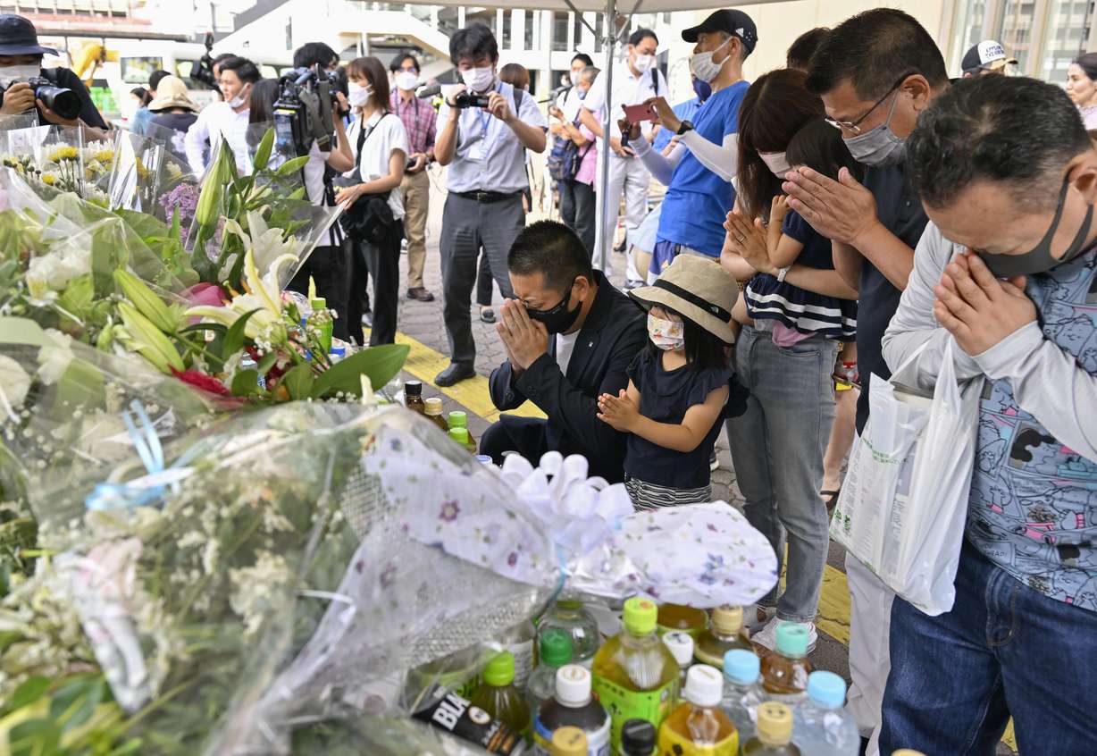 People pray at a makeshift memorial near the scene where the former Prime Minister Shinzo Abe was shot while delivering his speech to support the Liberal Democratic Party's candidate during an election campaign in Nara, Saturday. Abe, a divisive arch-conservative and one of his nation's most powerful and influential figures, has died after being shot during a campaign speech Friday in western Japan, hospital officials said.