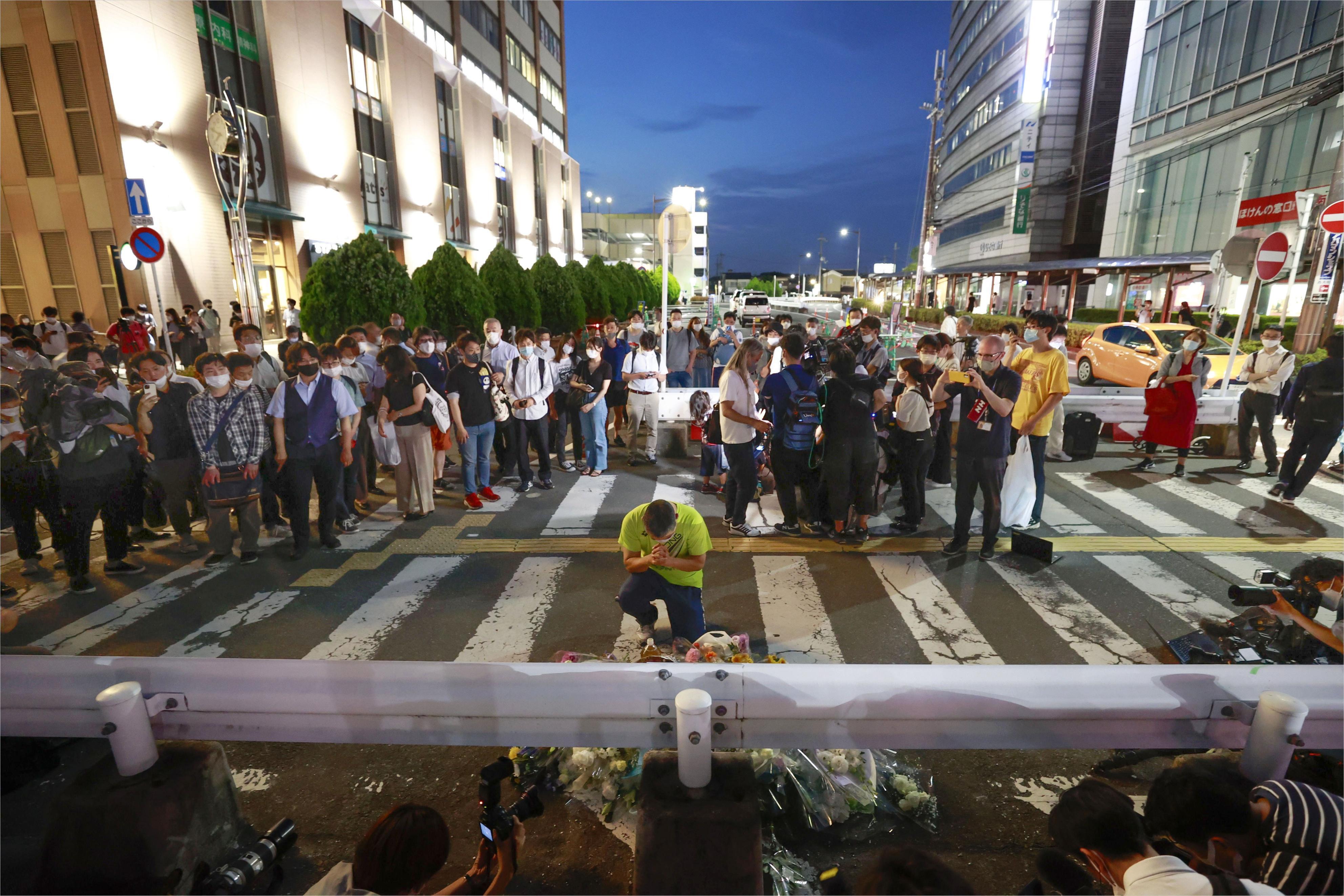 People pray at a makeshift memorial at the scene where the former Prime Minister Shinzo Abe was shot while delivering his speech to support the Liberal Democratic Party's candidate during an election campaign in Nara, Friday. Abe, a divisive arch-conservative and one of his nation's most powerful and influential figures, has died after being shot during a campaign speech Friday in western Japan, hospital officials said.