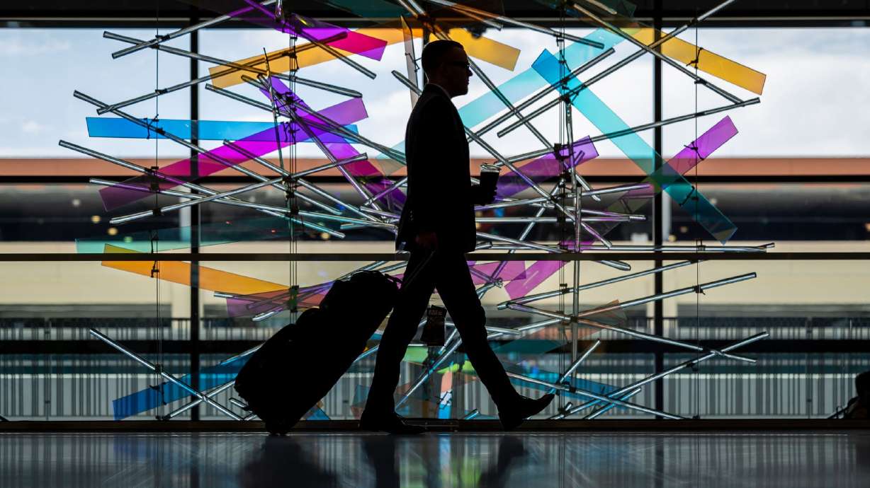 A traveler walks past “The Falls” sculpture at Salt Lake City International Airport in Salt Lake City on July 1. A majority of Utah residents are now considering scaling back or postponing summer travel plans in the face of ongoing inflationary pressures and record-high gas prices, according to new polling data.