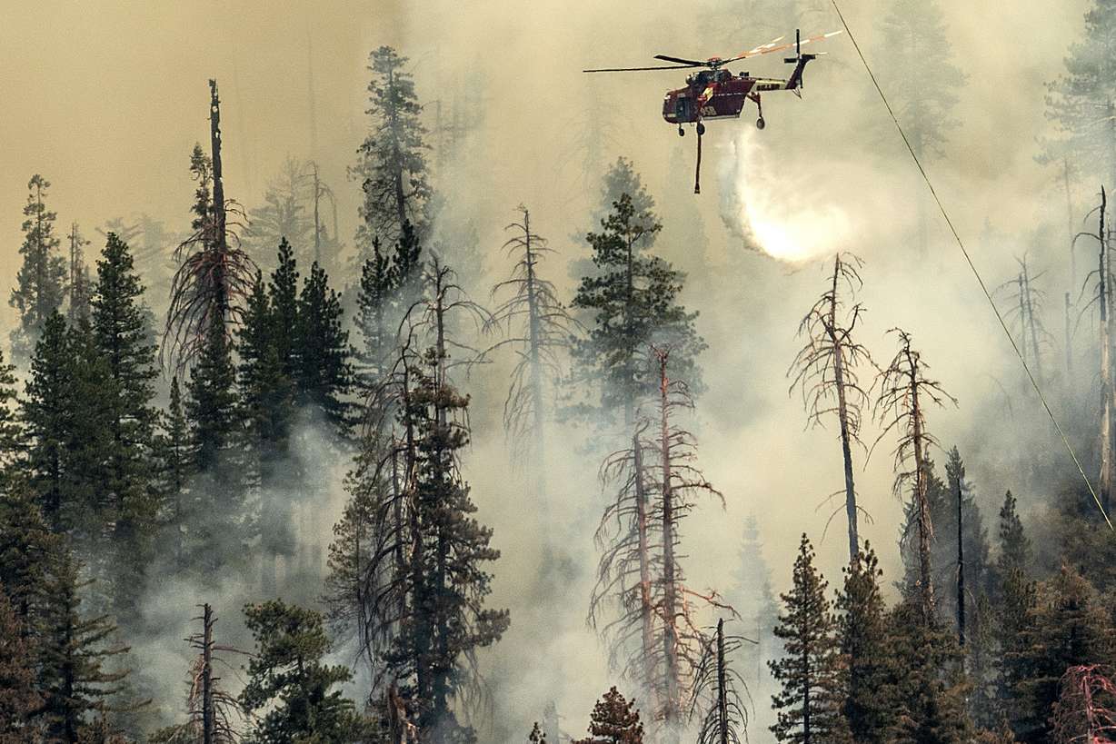Seen from unincorporated Mariposa County, Calif., a helicopter drops water on the Washburn Fire burning in Yosemite National Park, Saturday.