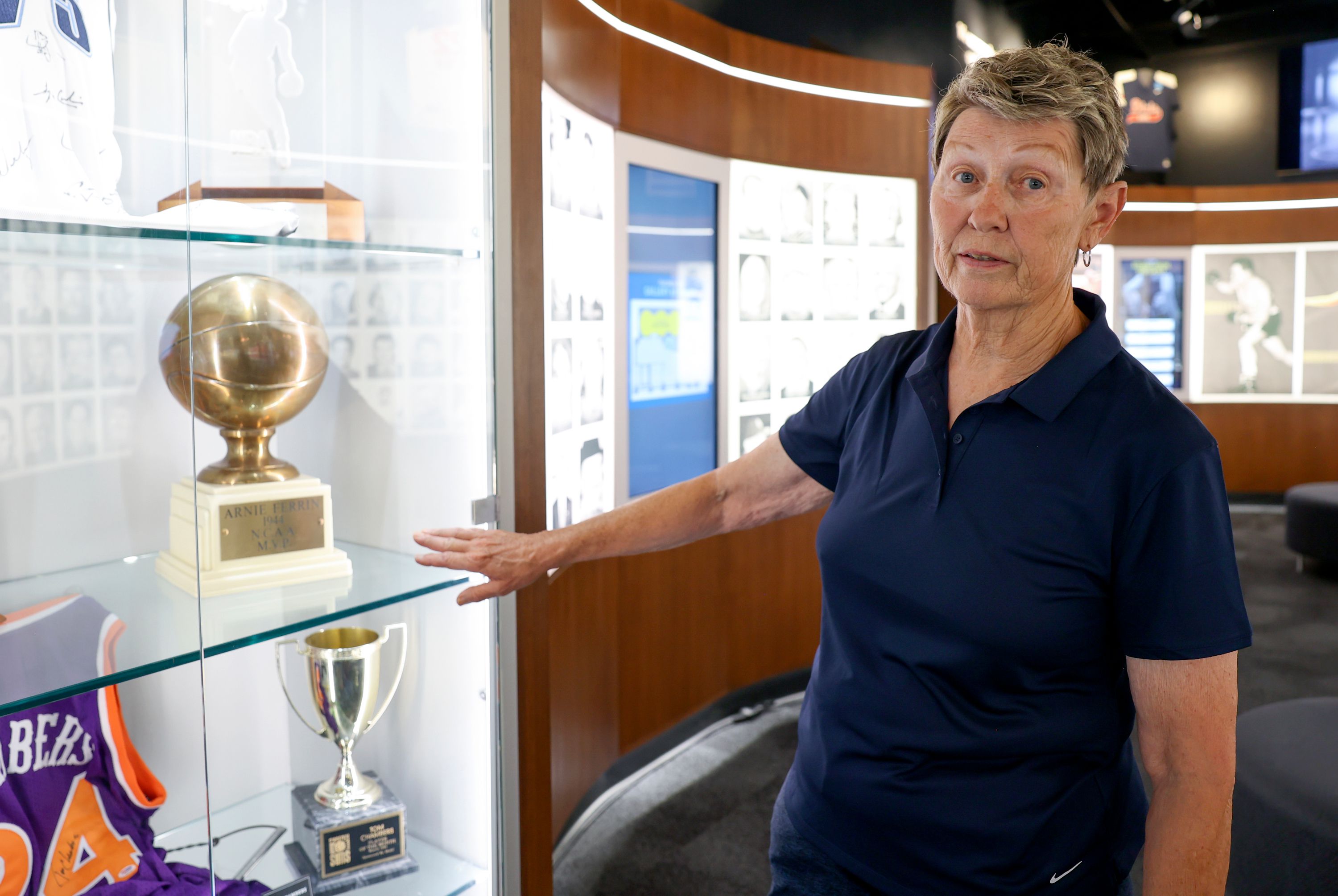 Norma Carr, former president of the Utah Sports Hall of Fame, shows Arnie Ferrin’s 1944 NCAA Most Valuable Player trophy on display in the Utah Sports Hall of Fame at City Creek Center in Salt Lake City on June 15.