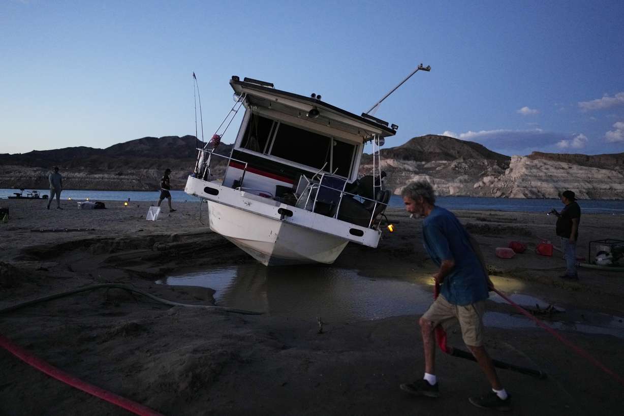 Craig Miller hauls a hose while trying to free his stranded houseboat at the Lake Mead National Recreation Area, June 23, near Boulder City, Nev. Miller had been living on the stranded boat for over two weeks after engine trouble and falling lake levels left the boat above the water level.