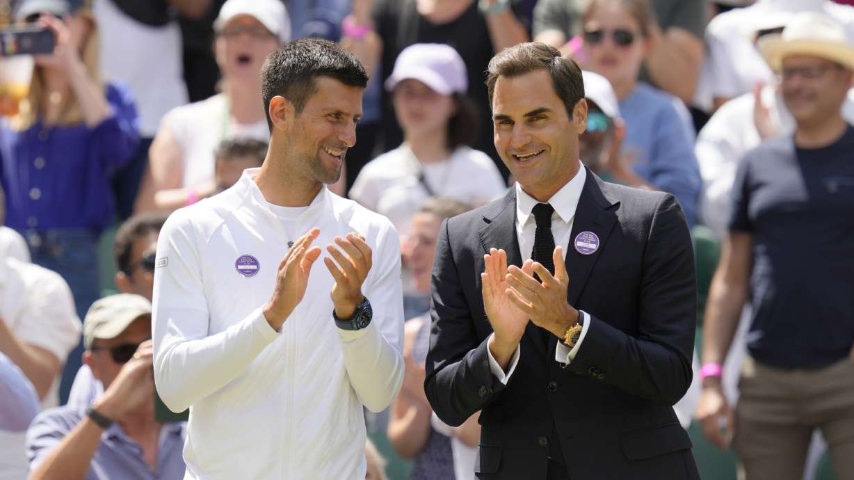 Serbia's Novak Djokovic and Switzerland's Roger Federer applaud during a 100 years of Centre Court celebration on day seven of the Wimbledon tennis championships in London, Sunday, July 3, 2022.