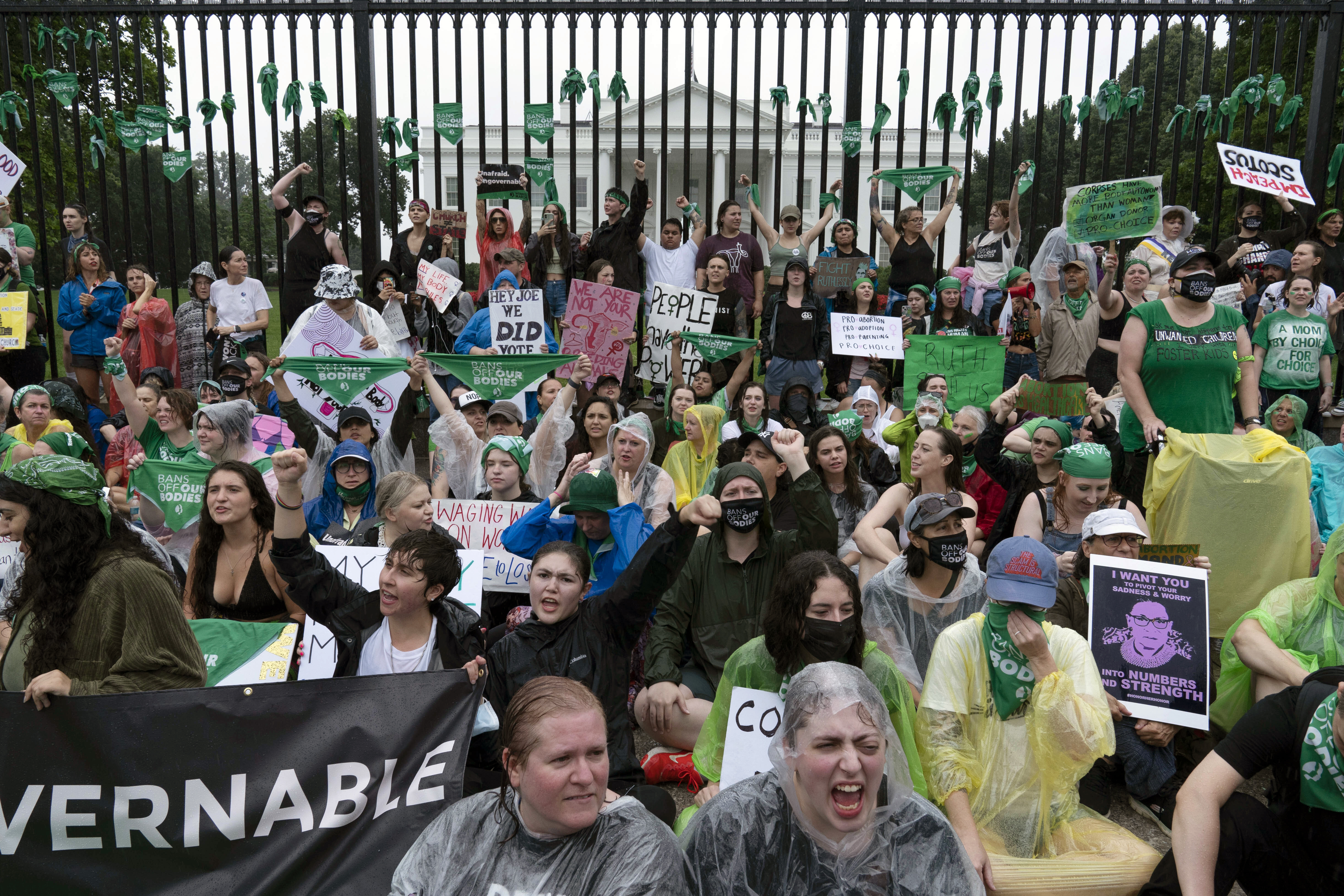 Abortion-rights demonstrators shout slogans after tying green flags to the fence of the White House during a protest to pressure the Biden administration to act and protect abortion rights, in Washington, Saturday. 