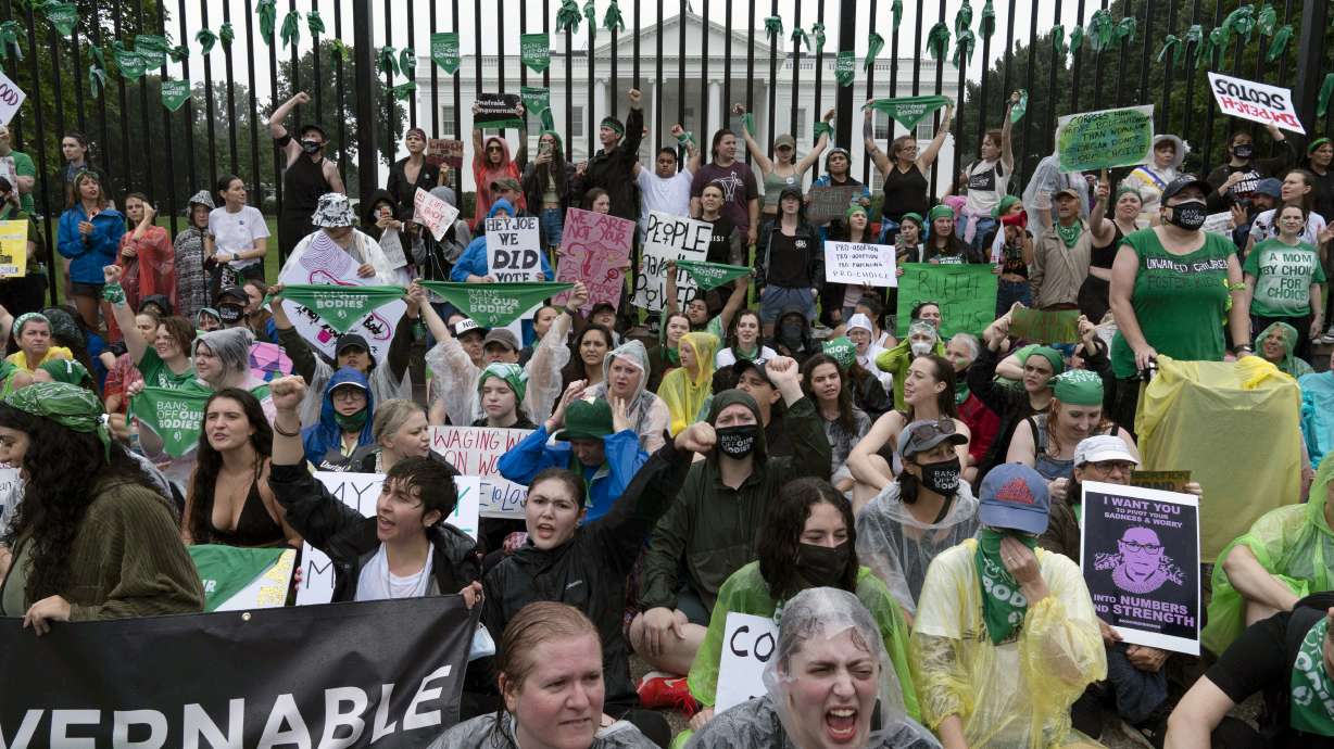Abortion-rights demonstrators shout slogans after tying green flags to the fence of the White House during a protest to pressure the Biden administration to act and protect abortion rights, in Washington, Saturday.