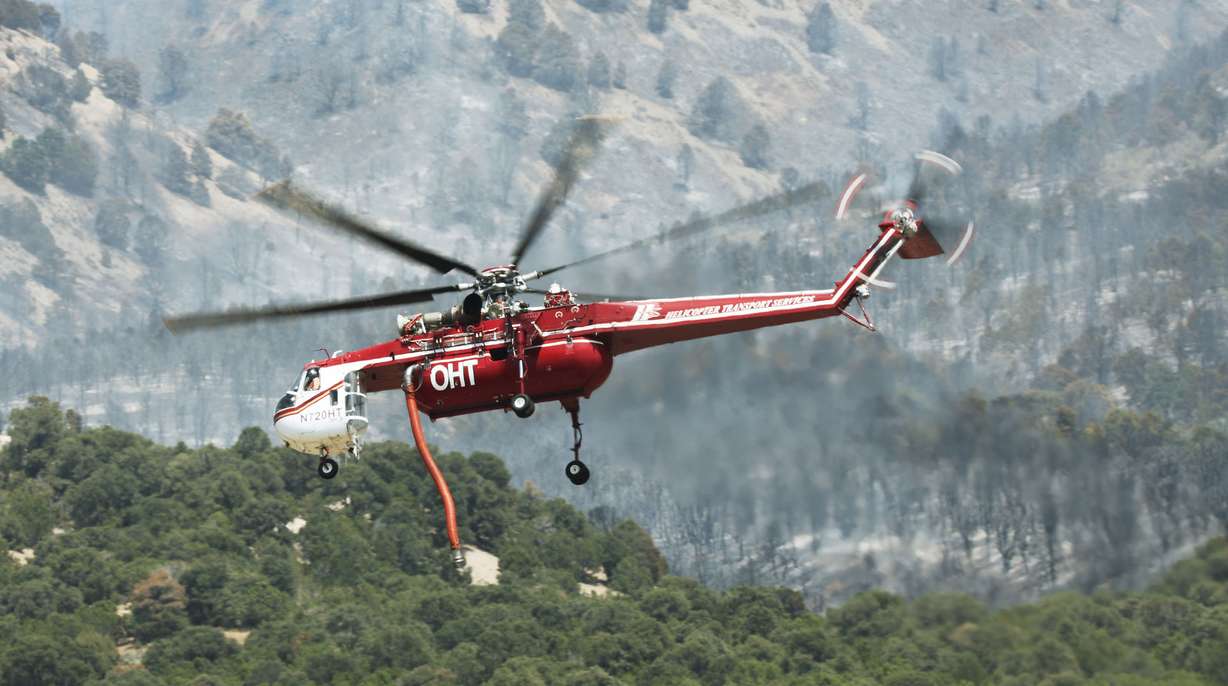 A helicopter picks up water to fight the Jacob City Fire near Stockton, Tooele County, on Monday.