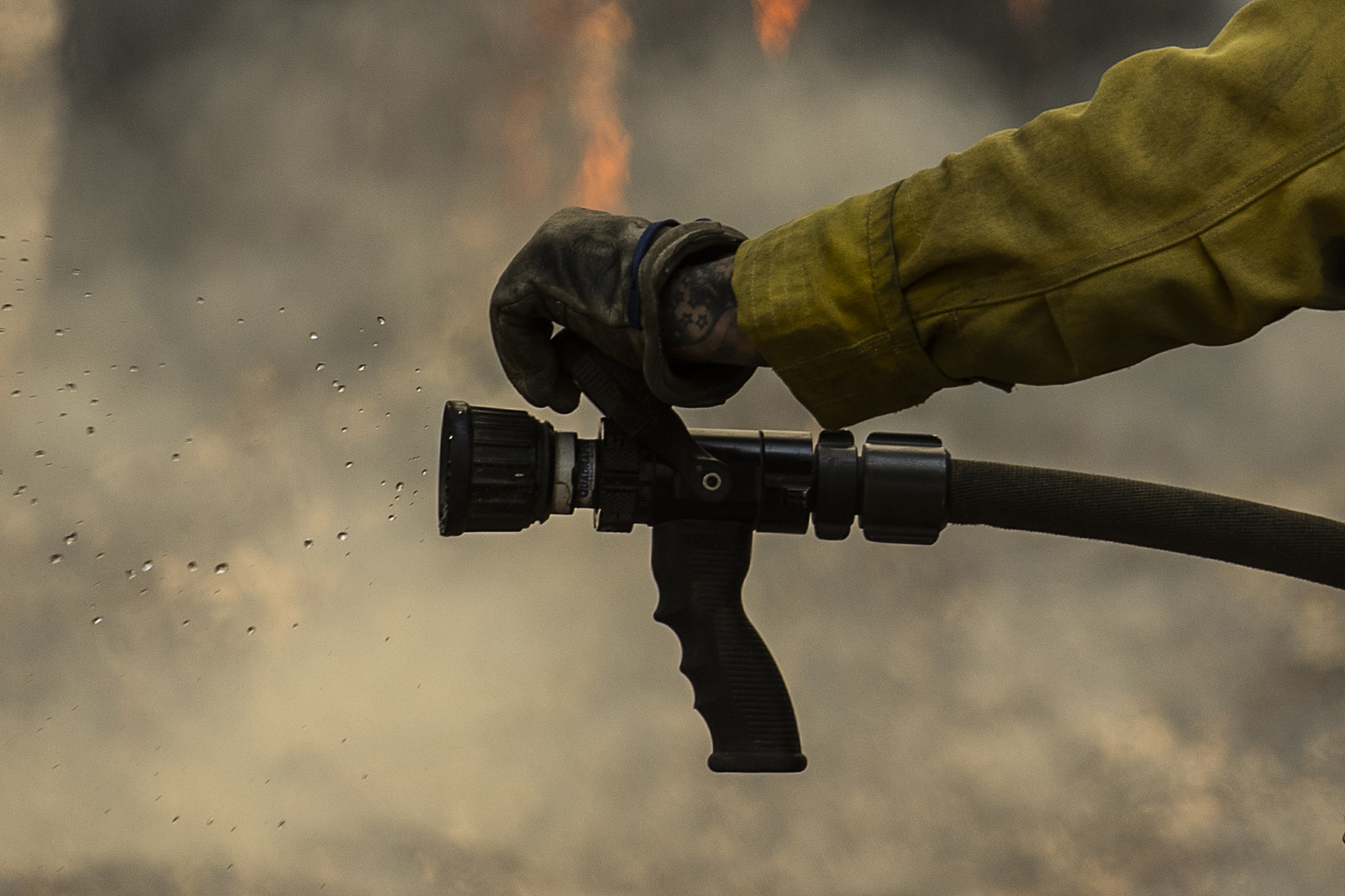 Water is seen from a hose as a CalFire firefighter monitors a backfiring operation against the Washburn Fire in Yosemite National Park, Calif. Monday.