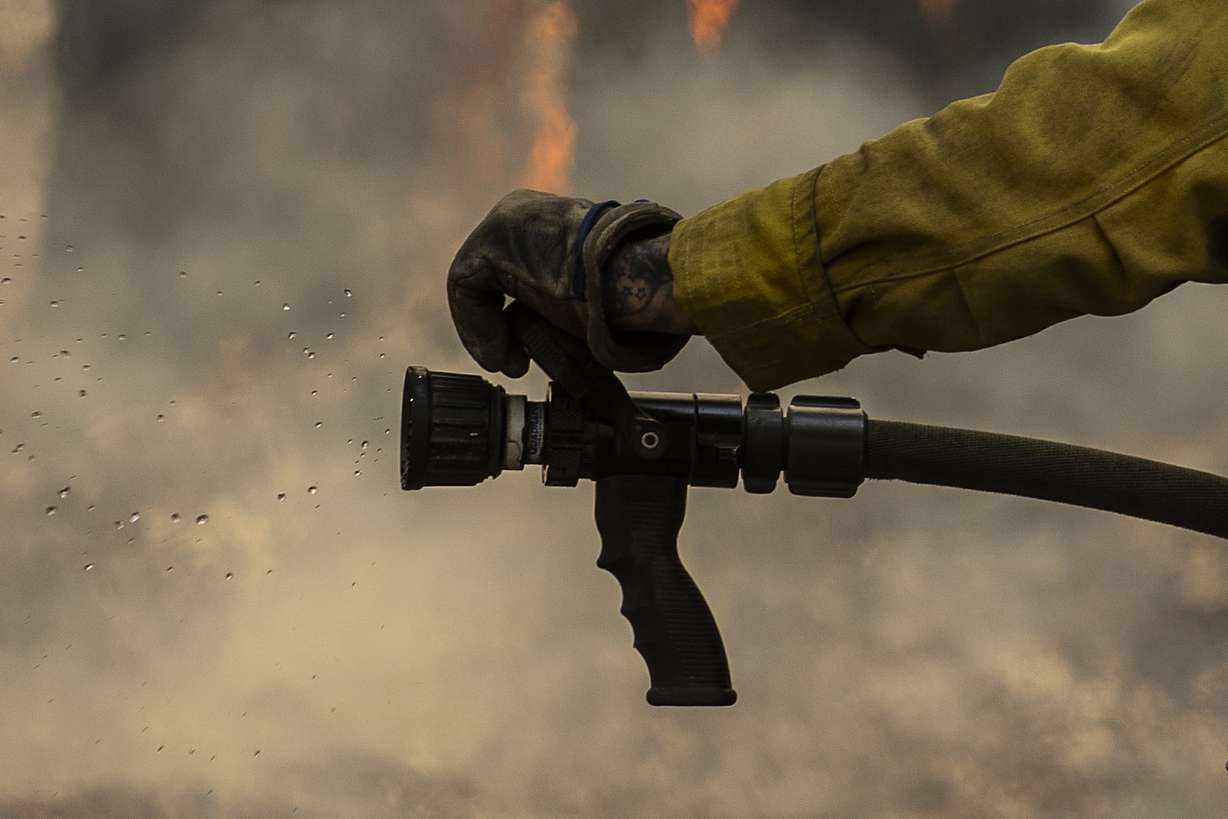 Water is seen from a hose as a CalFire firefighter monitors a backfiring operation against the Washburn Fire in Yosemite National Park, Calif. Monday.