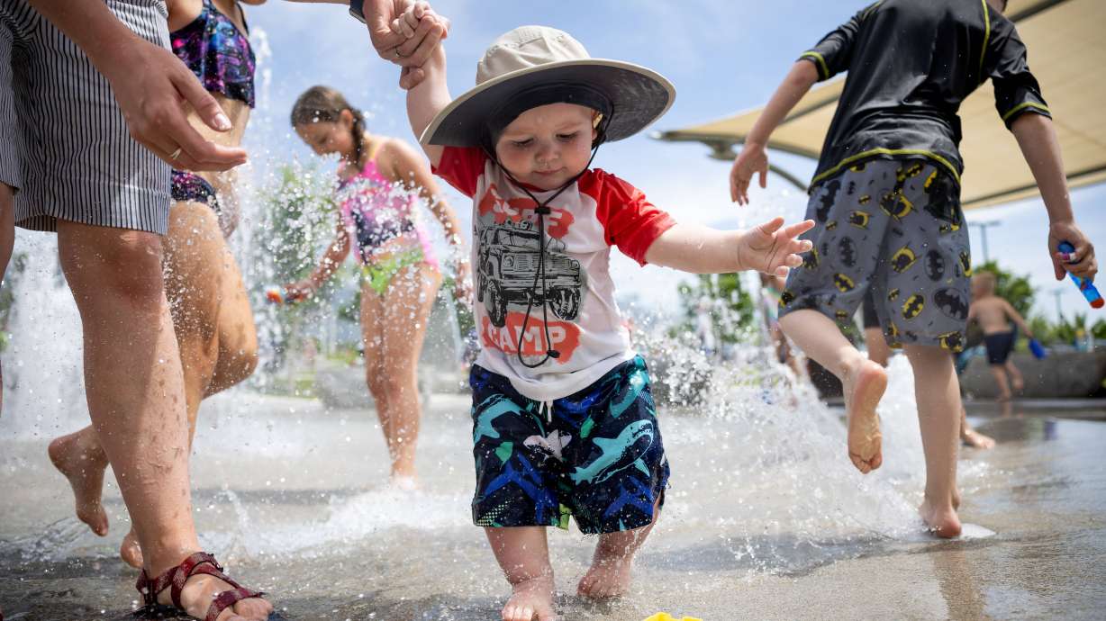 Catherine Stapley and her son, Jack, 11 months, play in the water at the Amphitheater Park splash pad in Sandy on June 9, 2022. Get in the summertime spirit with these activities that won't break the bank.