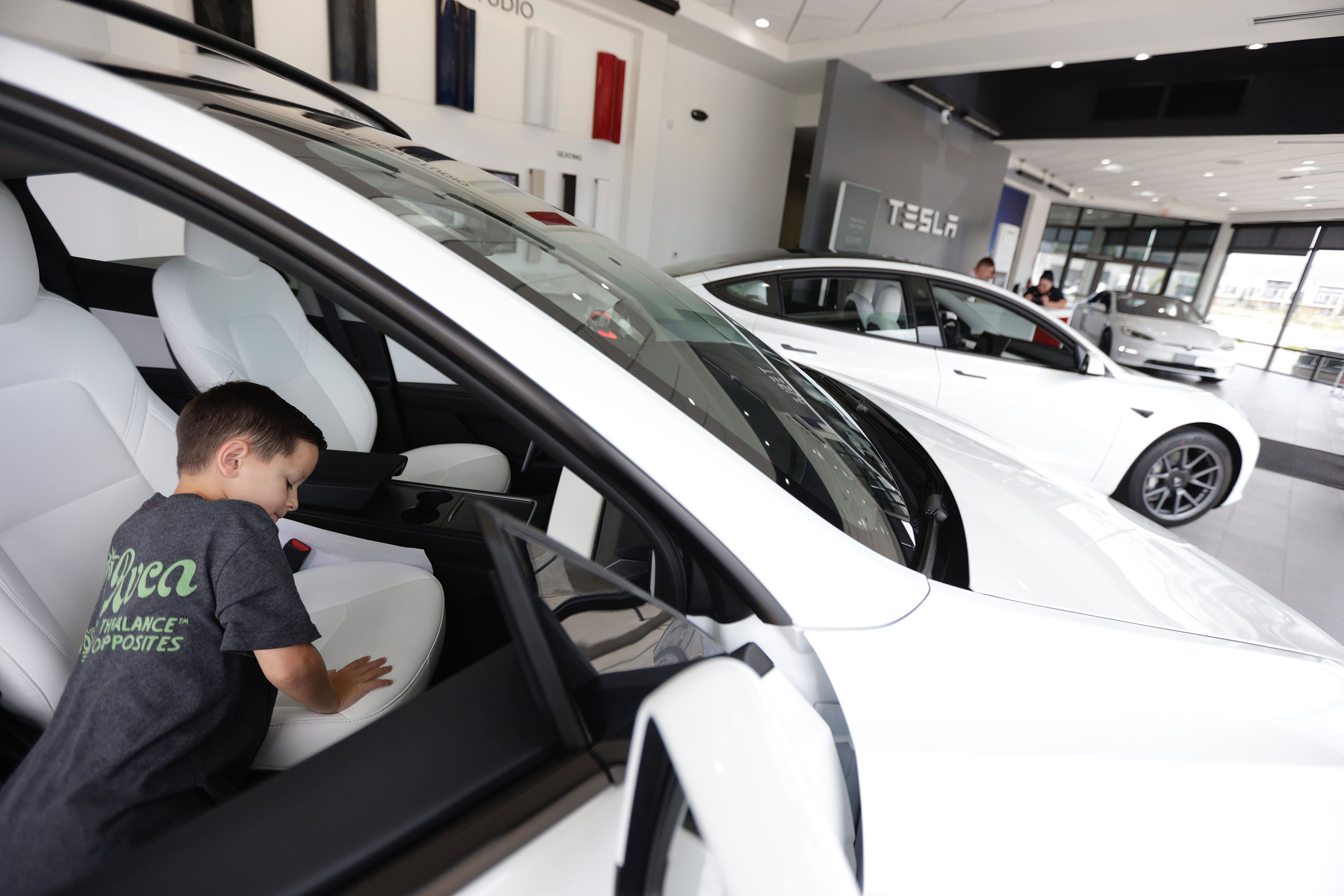 Tristan Galgano, 9, of Provo, checks out a Tesla with his parents, Tyrone and Maria Galgano, at the Tesla dealership in Salt Lake City on Tuesday. A new report finds that the biggest growth in clean fuel vehicle ownership is happening in central and rural areas.