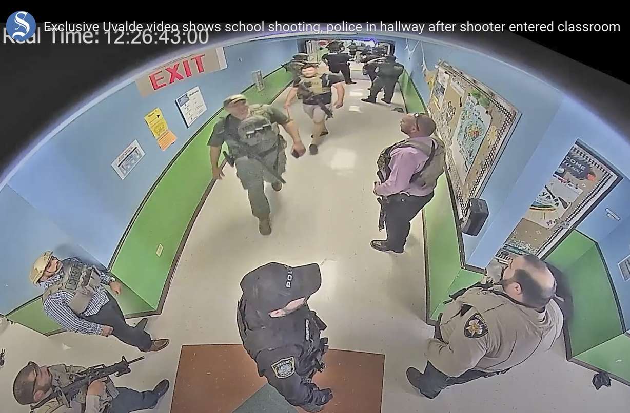 In this photo from surveillance video provided by the Uvalde Consolidated Independent School District via the Austin American-Statesman, authorities stage in a hallway as they respond to the shooting at Robb Elementary School in Uvalde, Texas, May 24.