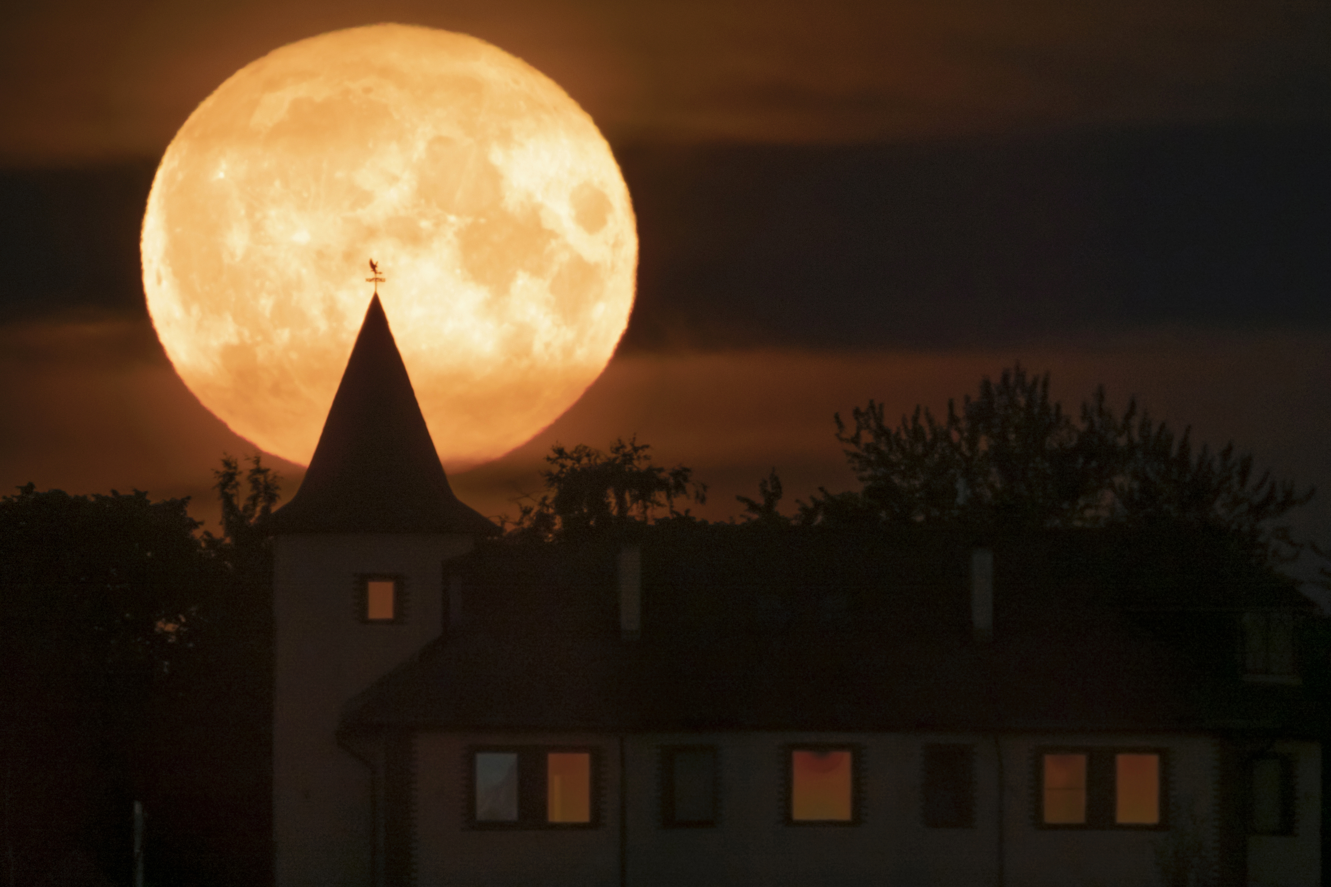 The full moon rises over a house in the village of Putilovo, 43 miles east of St. Petersburg, Russia, late Wednesday.