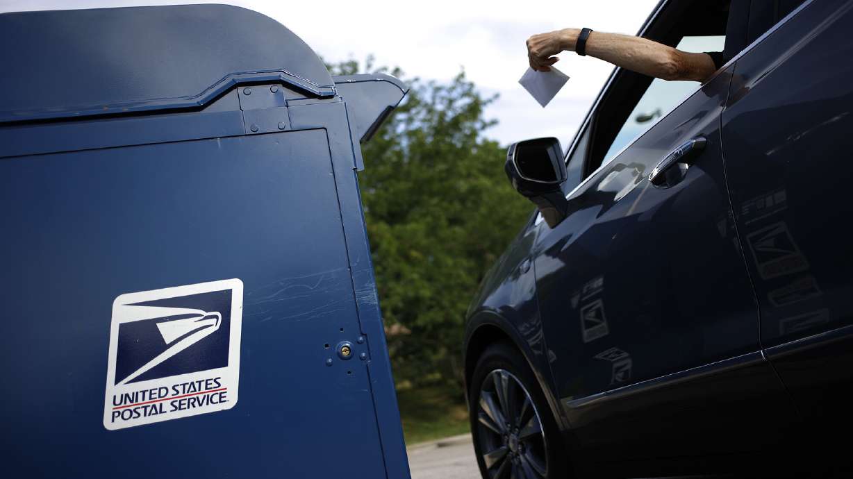A motorist drops a letter into a United States Postal Service mail drop box in Covington, Kentucky, on July 2. The cost of a US postage stamp just increased by a mere 2 cents.