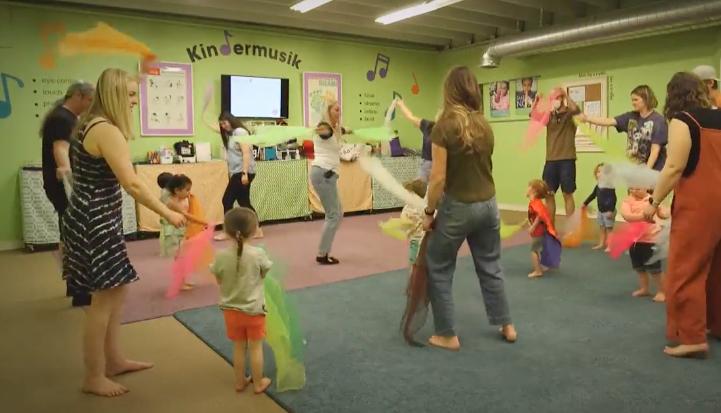 Adults and children dance to music at Kindermusik in Sugar House. Studies show that music helps foster child development in many ways.