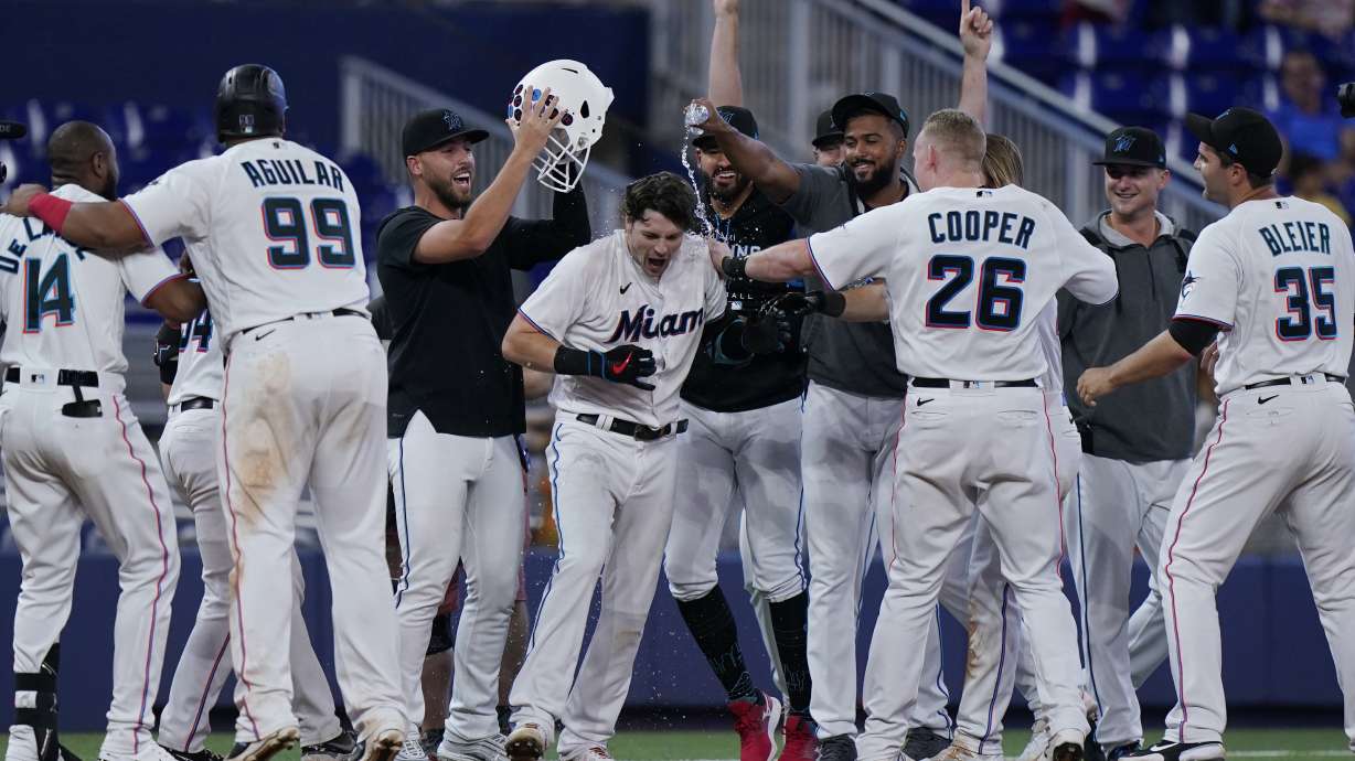 Teammates mob Miami Marlins' Brian Anderson, center, after Anderson tripled scoring Jesus Aguilar and Avisail Garcia during the 11th inning of a baseball game against the Pittsburgh Pirates, Thursday, July 14, 2022, in Miami.