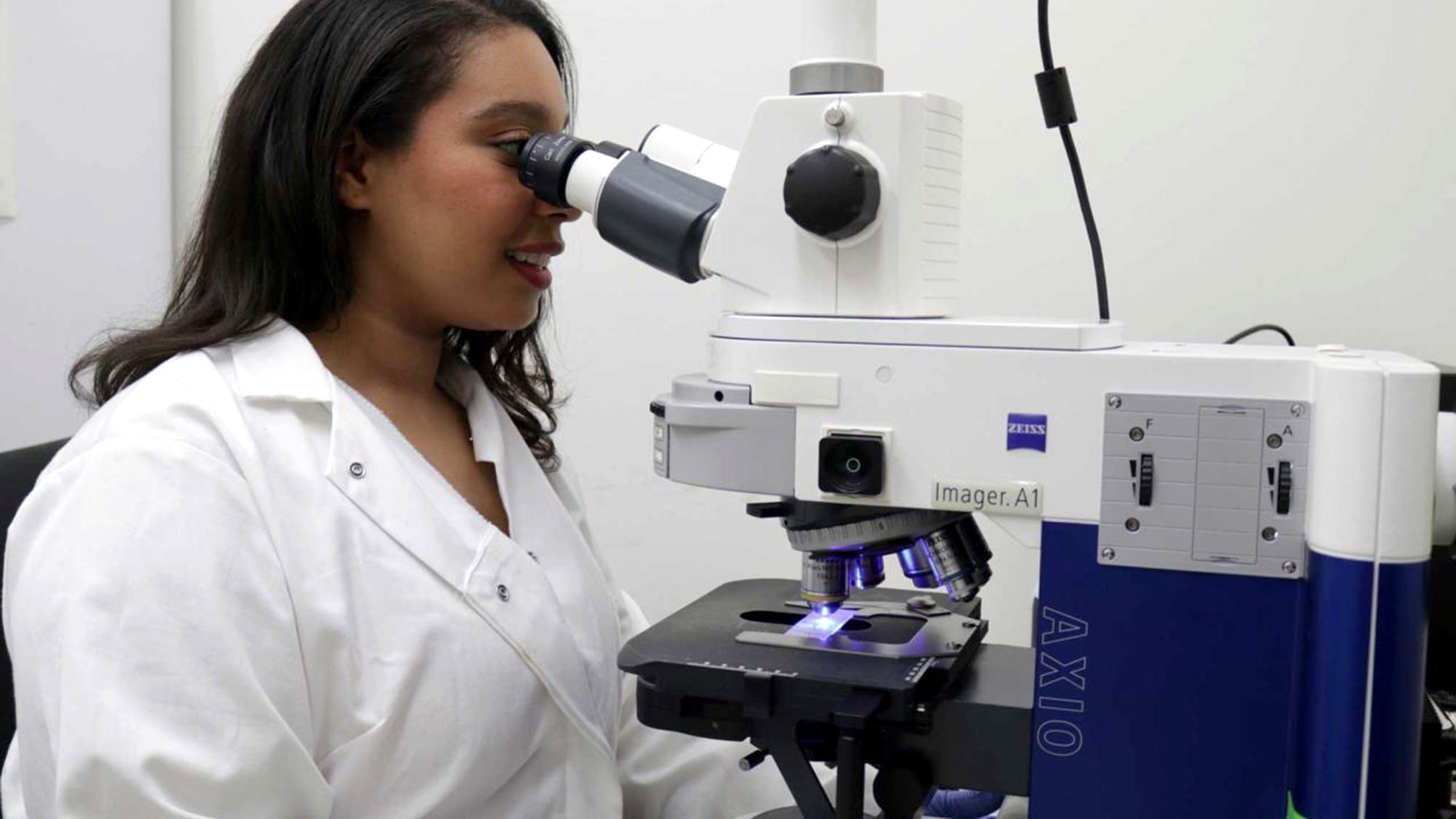 Alexia Williams uses a microscope to examine mouse brains in which RGS2 protein was experimentally increased. Increasing the RGS2 protein in the nucleus accumbens reduced the effects of stress on behavior in female mice.