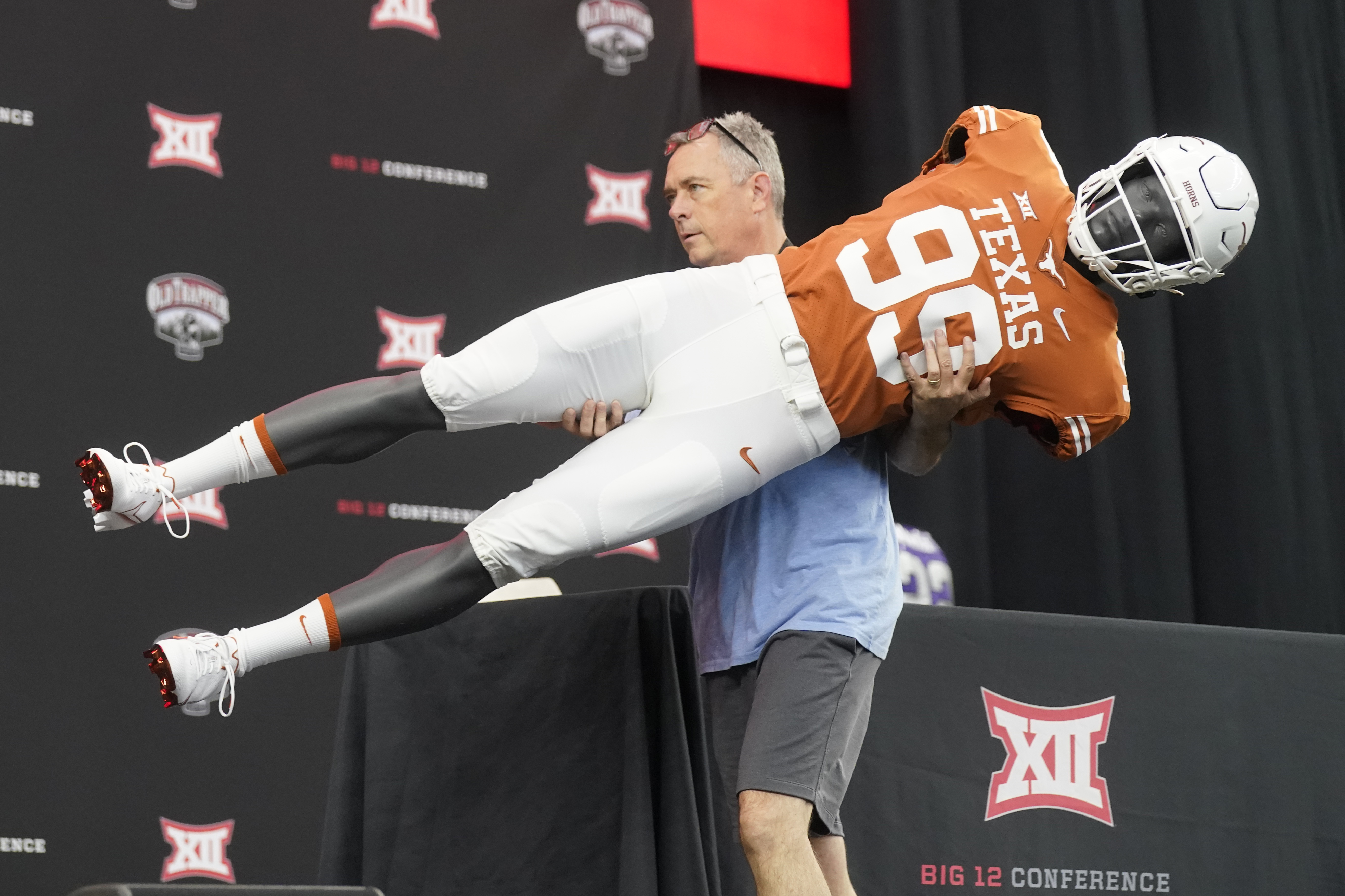 Brad Clements carries off a mannequin wearing a Texas football uniform as he dismantles the stage after the NCAA college football Big 12 media days in Arlington, Texas, Thursday, July 14, 2022. 